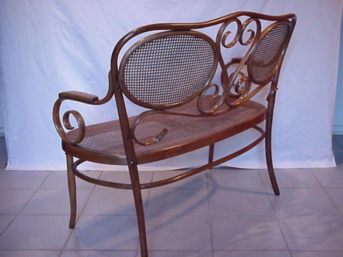 Thonet.
A bentwood Beech settee with wonderful scrollwork decoration to the back and to the arms with a caned seat and a caned back.