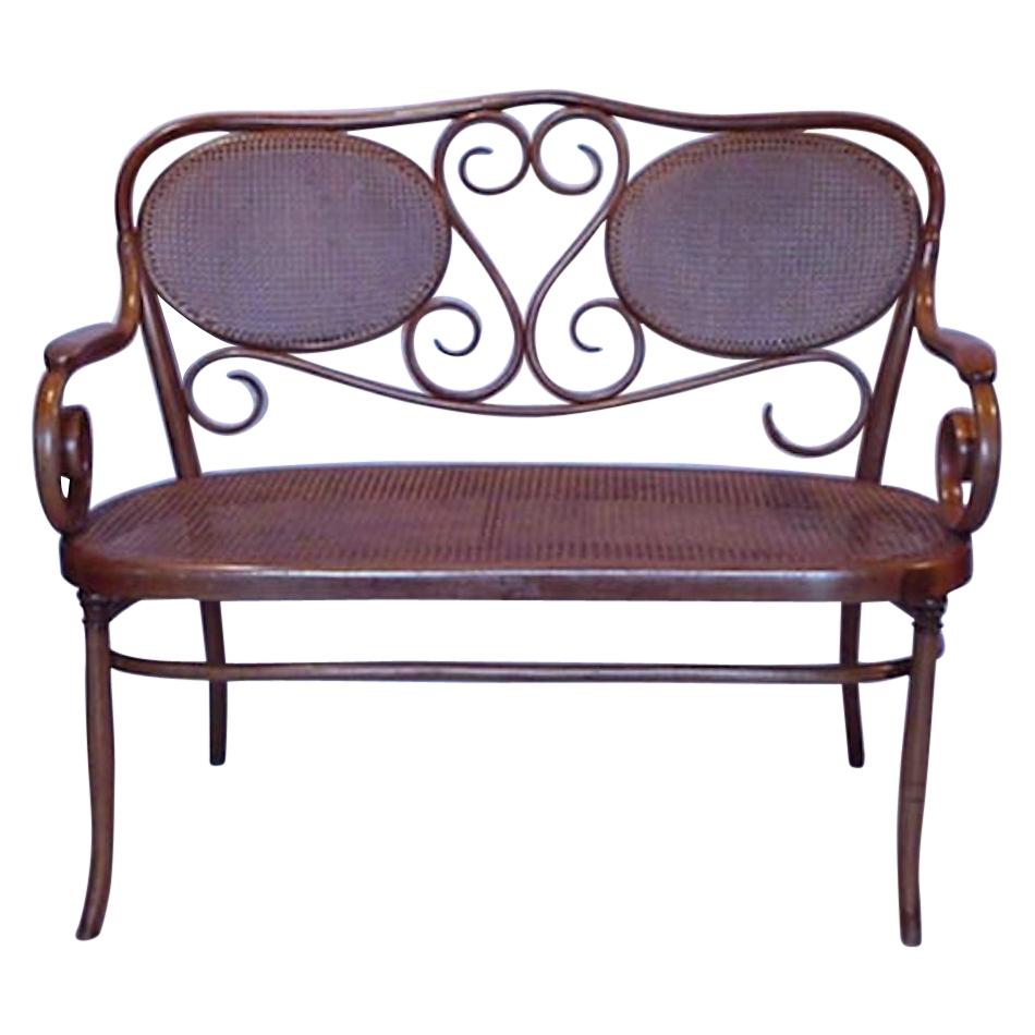 Thonet, A Bentwood Settee with Scrollwork Decoration with a Caned Seat & Back