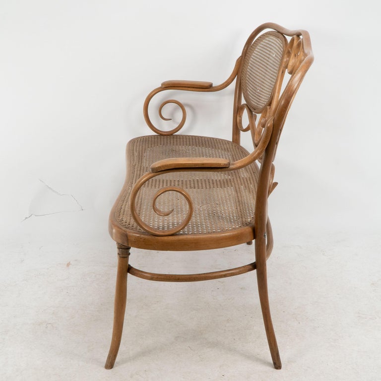 Divano in legno curvo con decorazioni a volute e sedile e