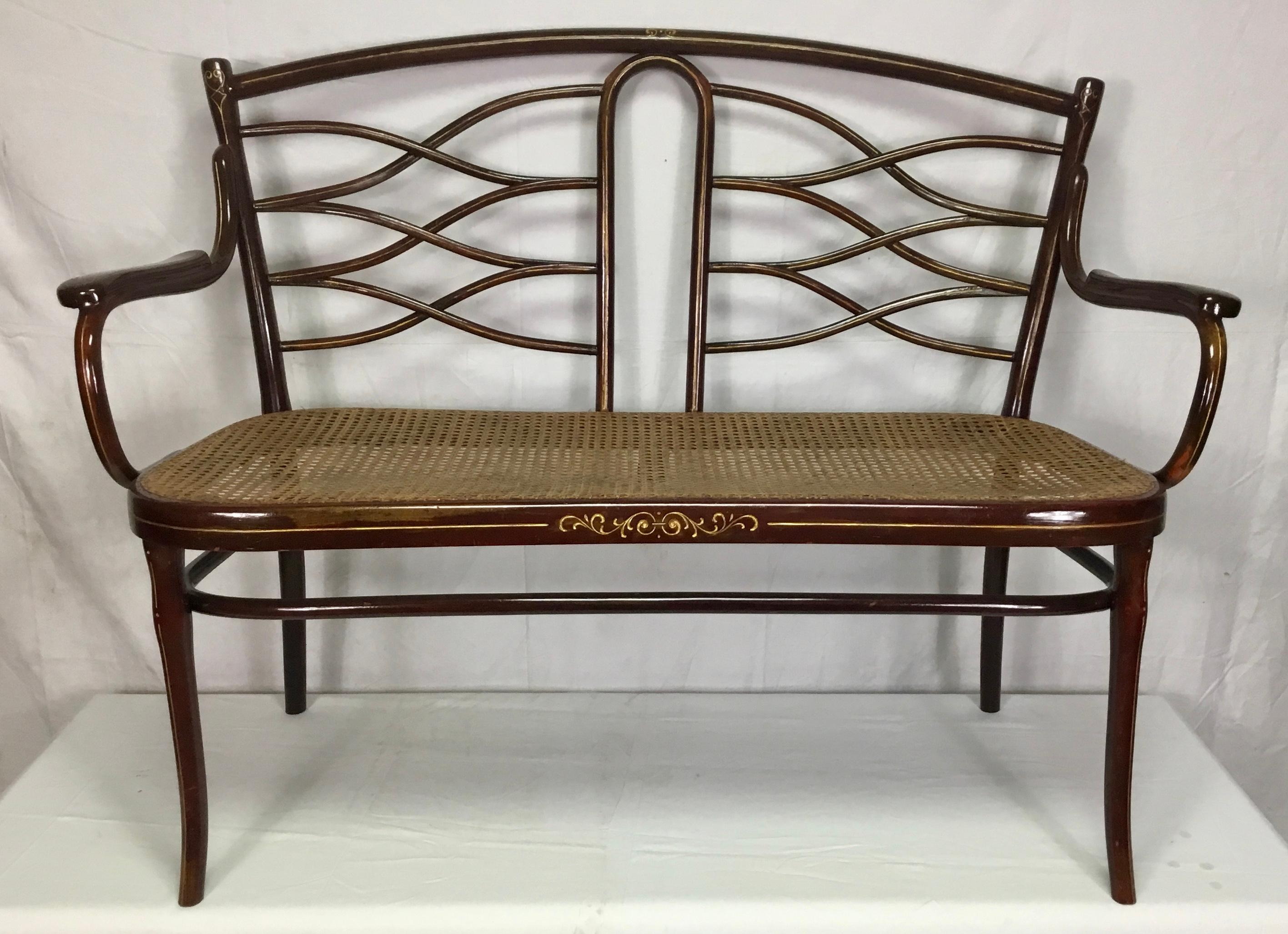 This beautiful bentwood banquette by Thonet, Austria, dates back to the late 19th century.
Its elegant bentwood frame has been highlighted with gold coloured detailing and the seat is in cane.
The original label is still present underneath as shown
