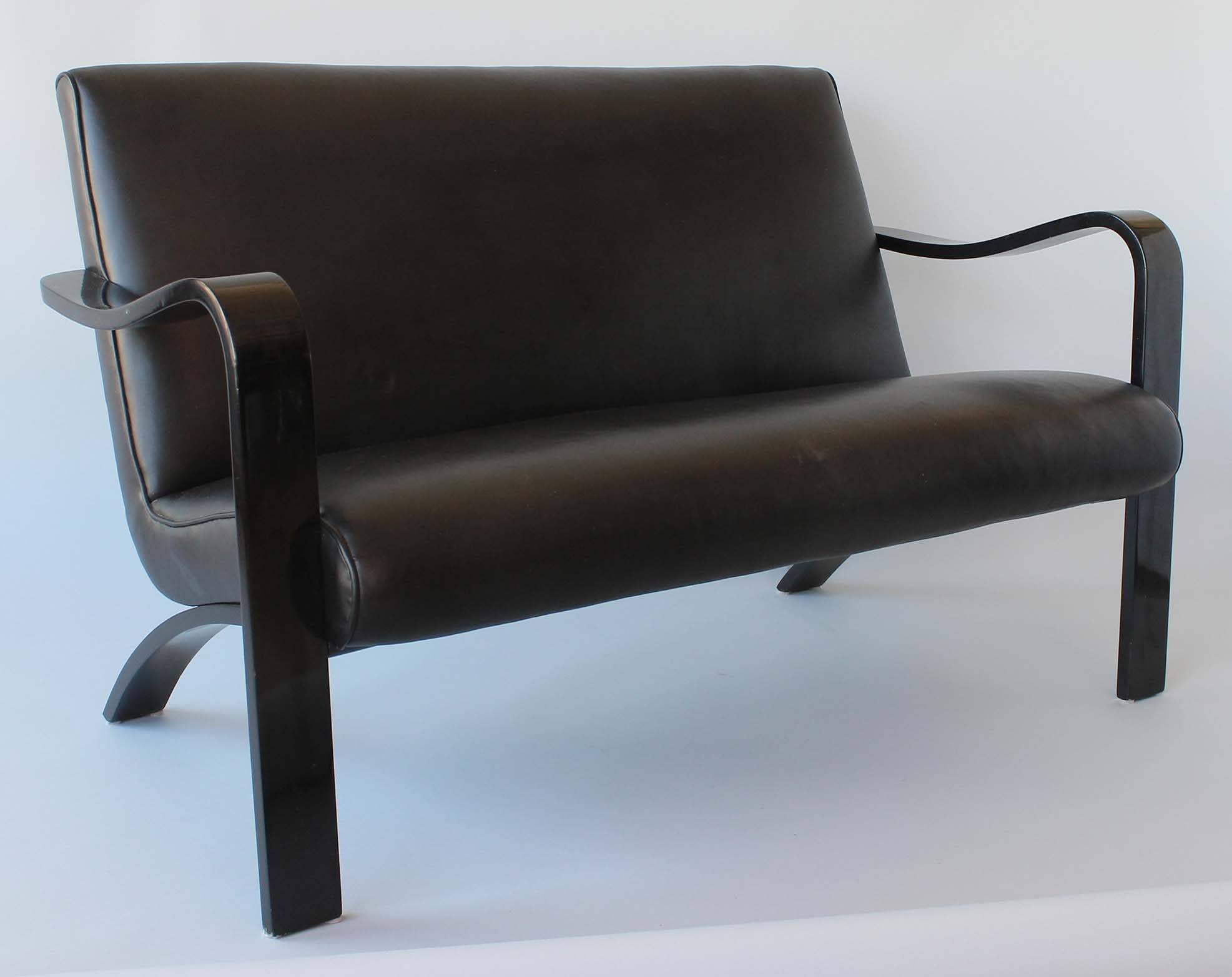 A midcentury bentwood sofa or love seat finished in black lacquer, with faux leather upholstery by Thonet.