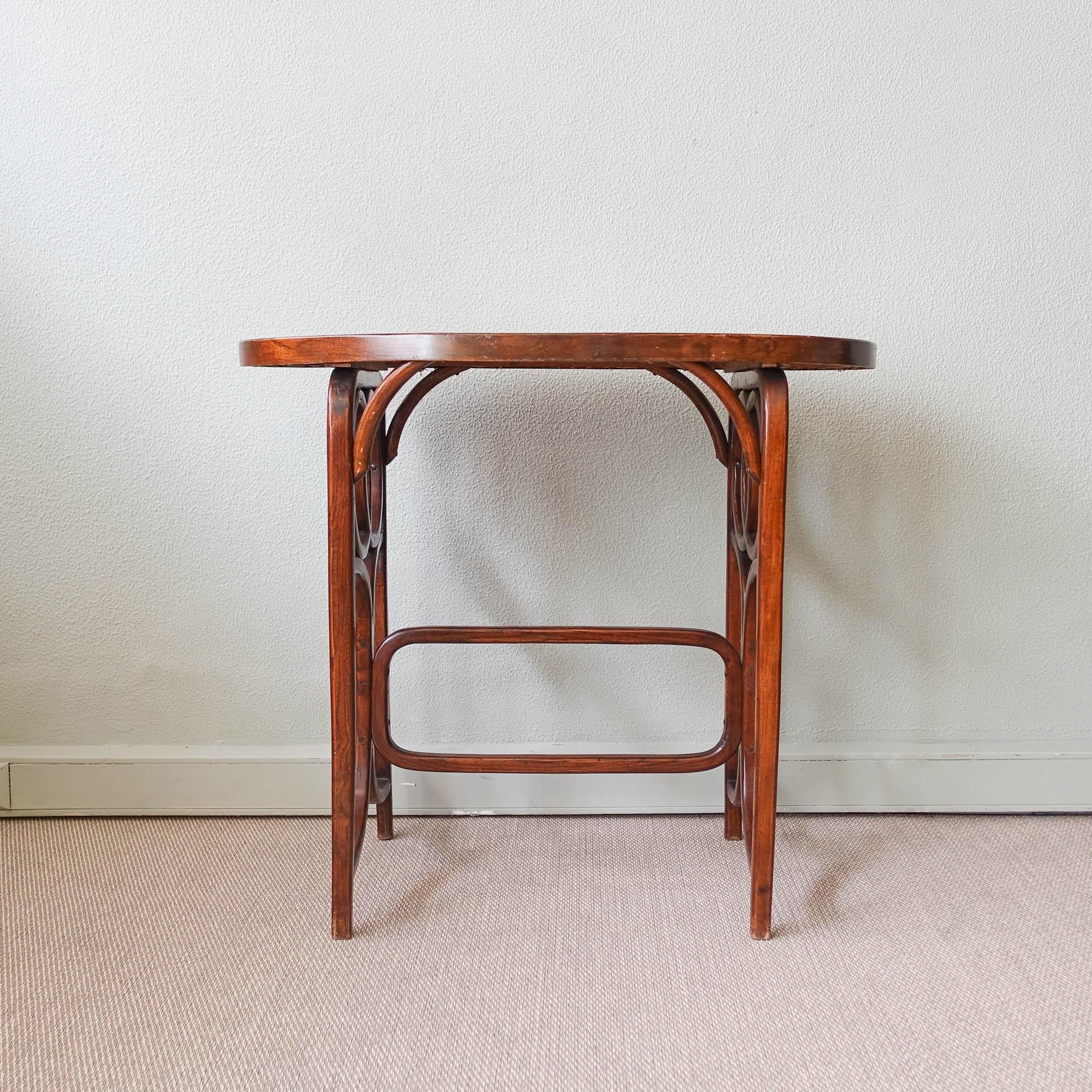 This bistro table was designed and produced by Thonet, in Austria, during the 1940's. It is made of cane wood and bentwood technique, with glass on top to protect. It is in original and good vintage condition.