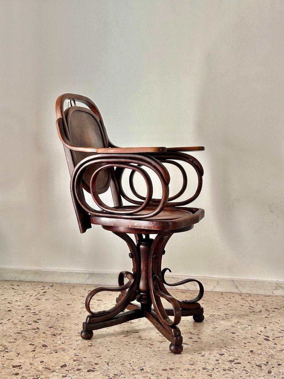 Swivel chair made entirely of solid wood. The backrest and seat are round in shape. On the back of the backrest and on the seat there are some floral design workmanship. The oval armrests are made of curved wooden thick slats. The base is made up of