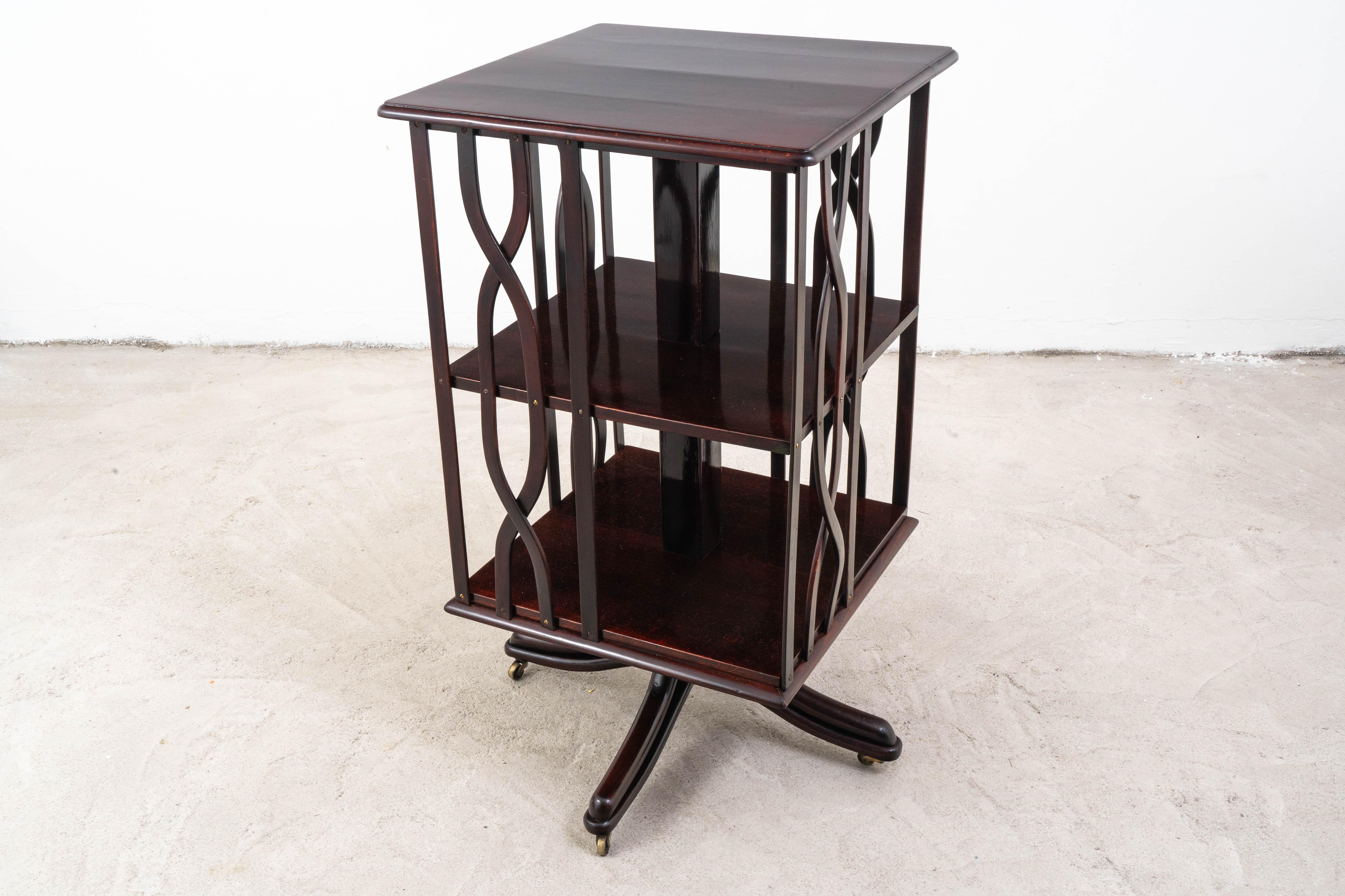 Dieser elegante drehbare Zeitungsständer mit der Modellnummer 11651 wurde vor 1904 von dem renommierten Möbelhersteller Gebrüder Thonet in Wien entworfen. Das Regal ist aus hochwertigem Buchenholz gefertigt, das in einer satten Mahagonifarbe gebeizt