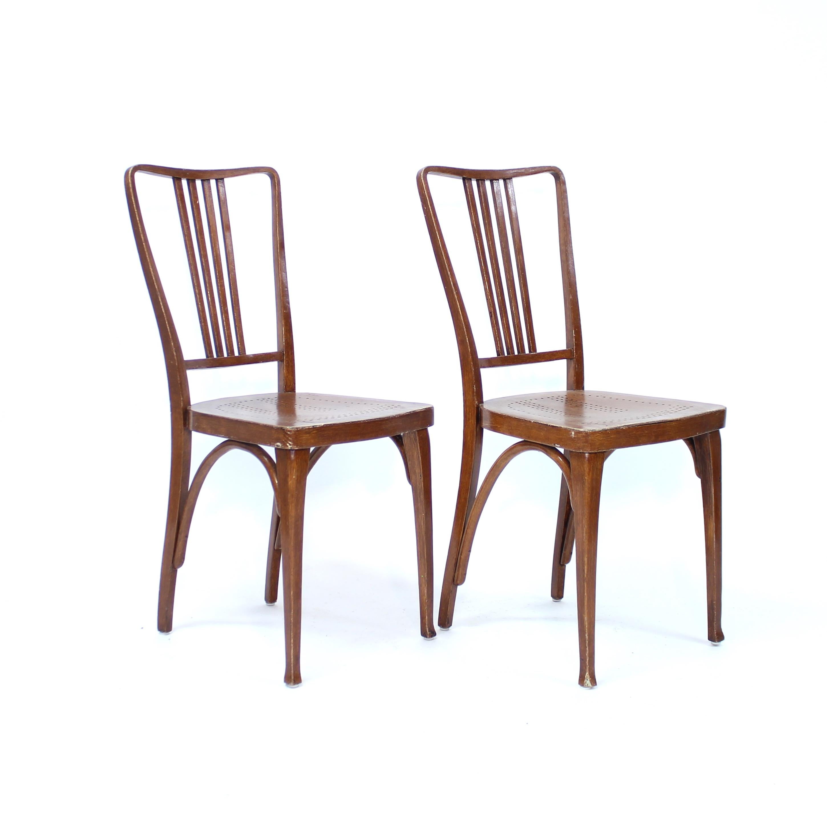 Raro par de sillas de madera curvada fabricadas por Thonet a principios del siglo XX. Ambas sillas tienen un bonito acabado de madera pintada de imitación que es antiguo, pero muy probablemente no original de la silla. Estampado por el fabricante en