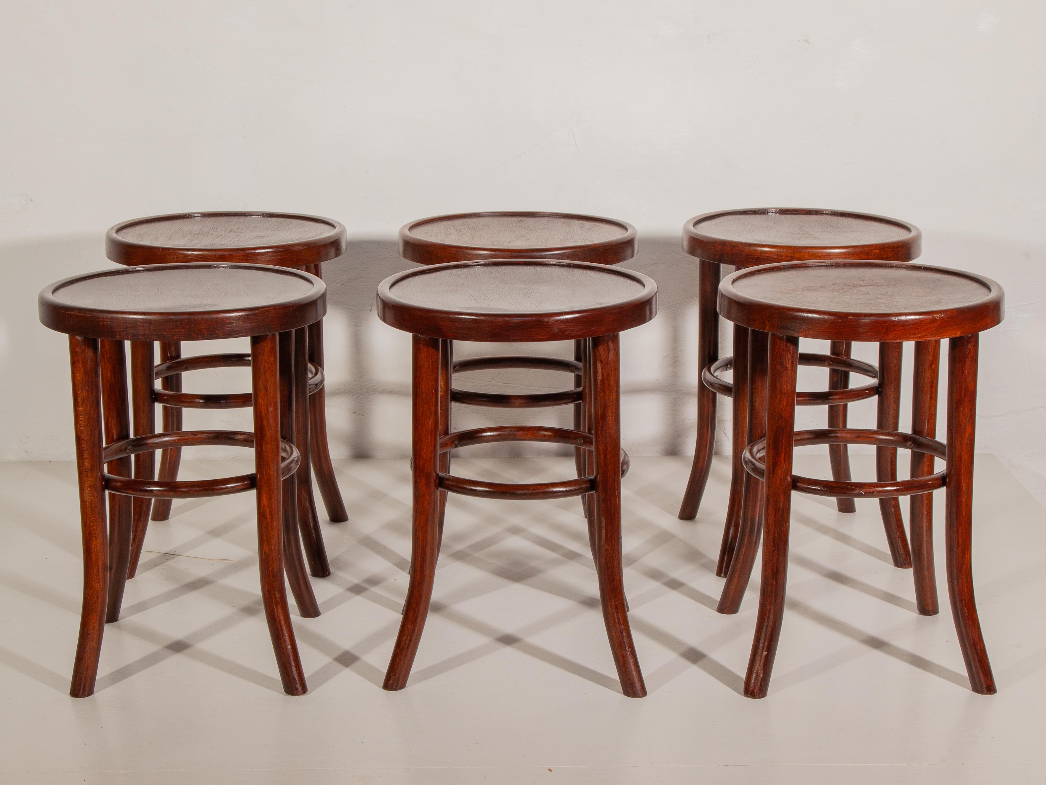 Un juego de seis taburetes de madera curvada de Thonet en su estado original. Los taburetes son de madera de haya curvada, con un segundo aro de madera curvada bajo el asiento para mayor estabilidad. Este principio de construcción fue desarrollado