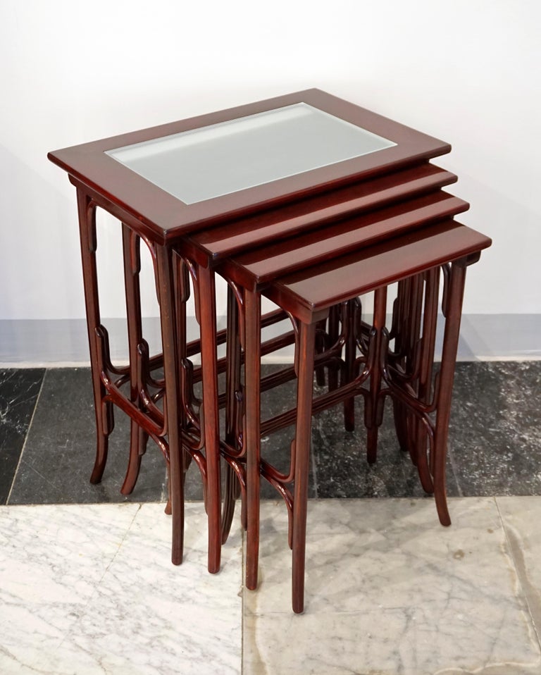 High-quality handcrafted placemat, beech bentwood, stained mahogany, shellac hand-polished:
Four nesting side tables in different sizes with an elegant design, the largest of the tables with a smoked glass inlay on top.

Manufactured by Thonet