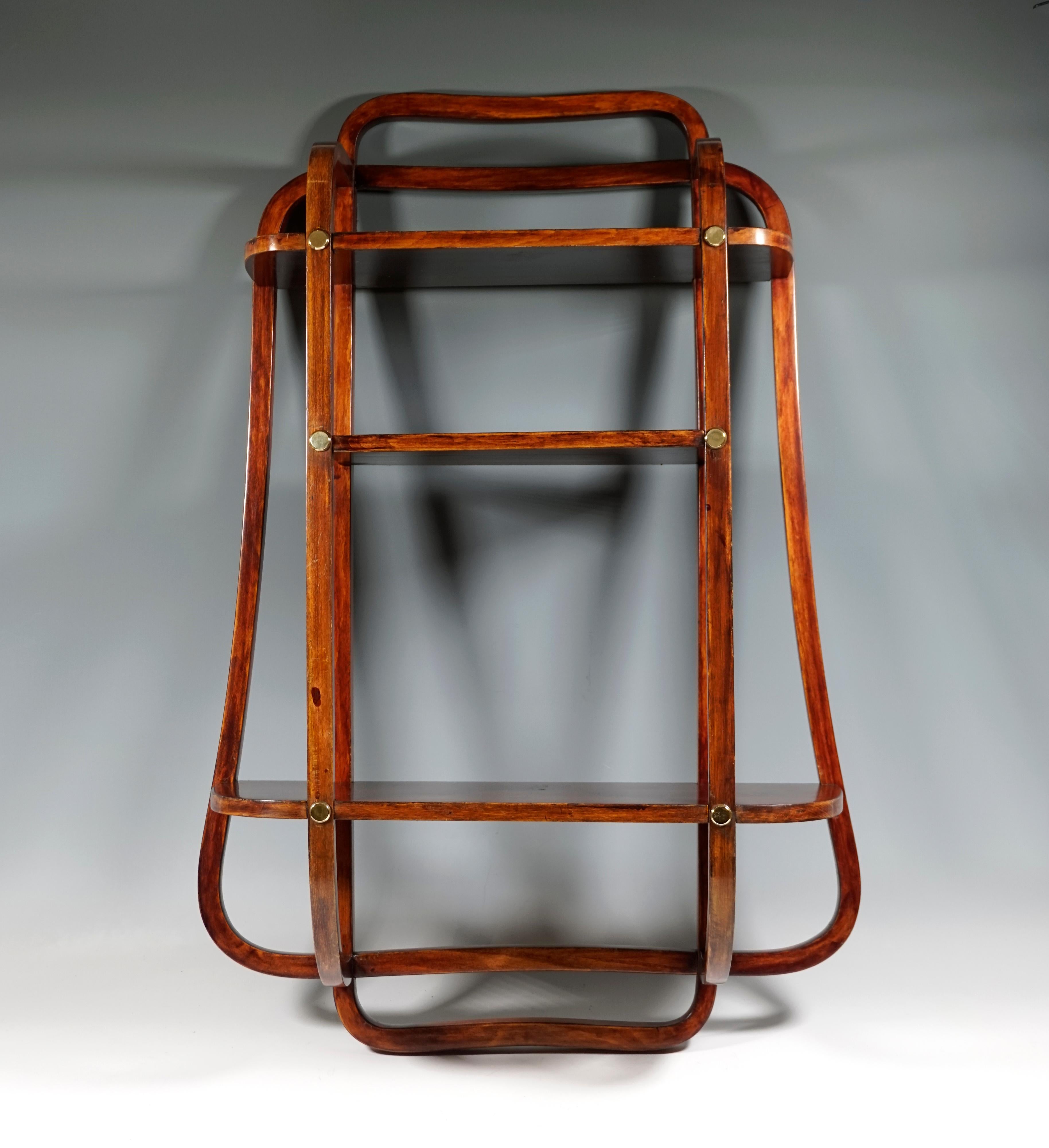Elegantly shaped etagere with four large storage levels, the straight uprights slightly flared in the lowest area, decorative, openwork struts in the form of repeating stylized containers on the sides, a circumferential rail attached to the top