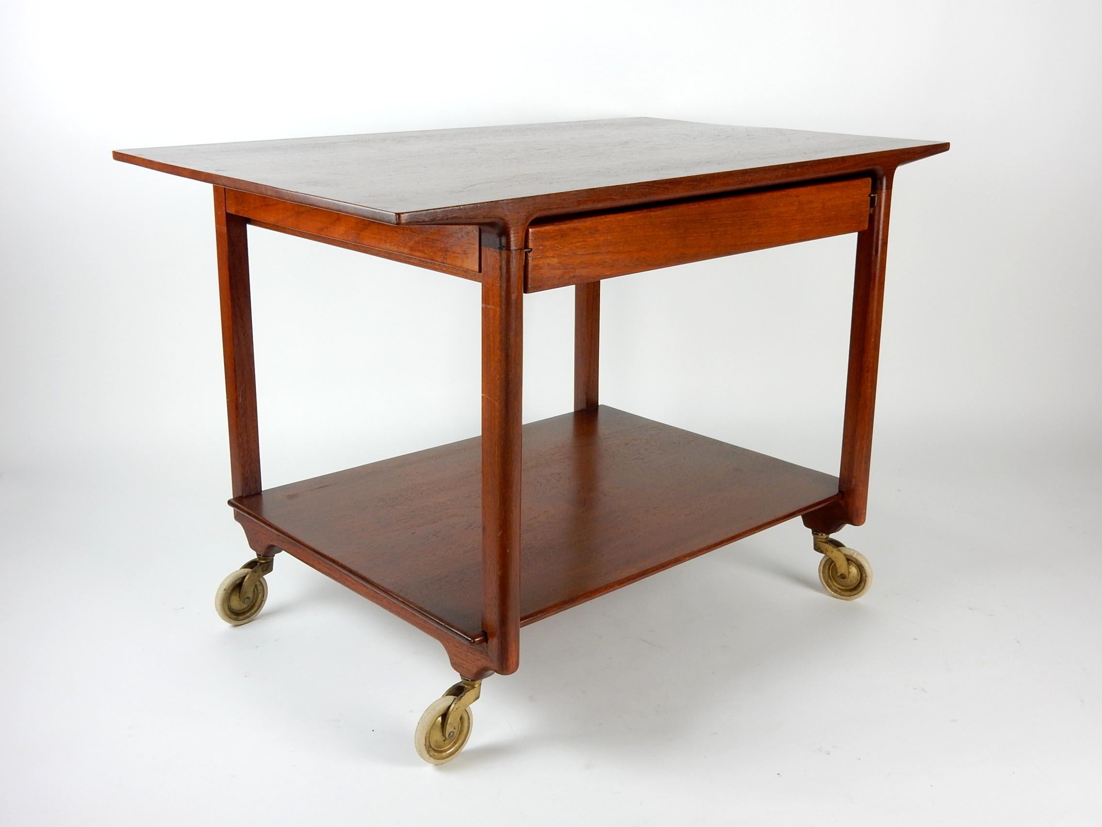 Simplistic midcentury Danish service cart from Thorald Madsens.
Attributed to designers Edvard and Tove Kindt-Larsen.
Sold teak with 2 sided drawers. Brass casters with white rubber wheels.
Thorald Madsens plate inside drawer as pictured.
This