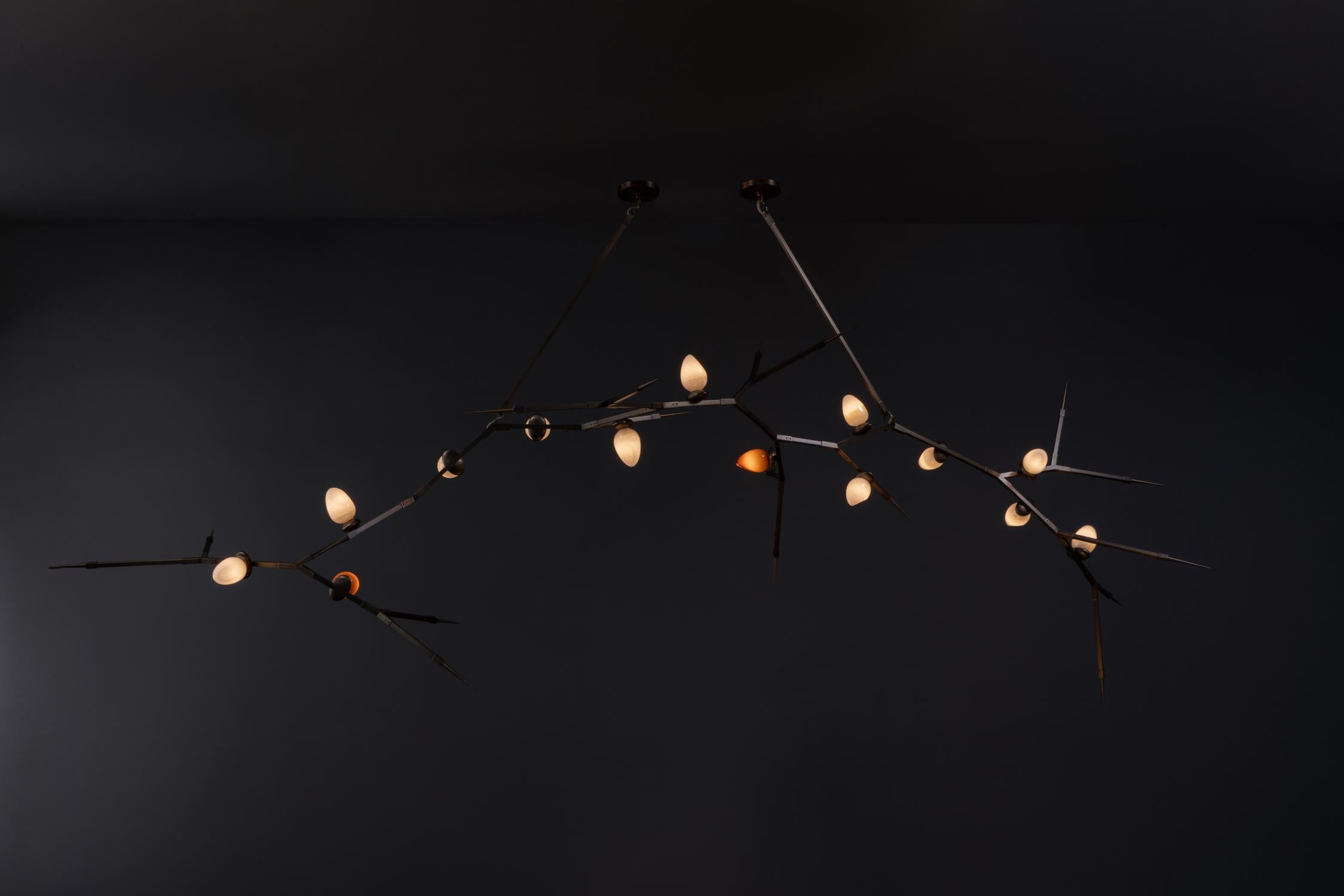Le lustre Thorn 100 (14) est un lustre mobile évolutif composé de quatorze diffuseurs en verre soufflé suspendus à deux tiges distinctes. Les diffuseurs en verre soufflé à la main sont proposés dans une gamme de finitions étonnantes appliquées à la