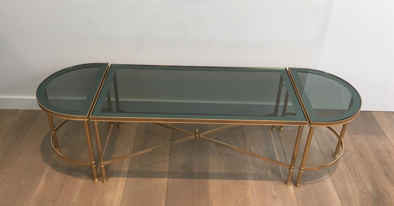 This tripartite coffee table is made of 3 elements made of gold gilt nickel with blueish glass tops mirrored on their surround. This coffee table is composed of a main rectangular coffee table with a pair of rounded side tables on each part of the