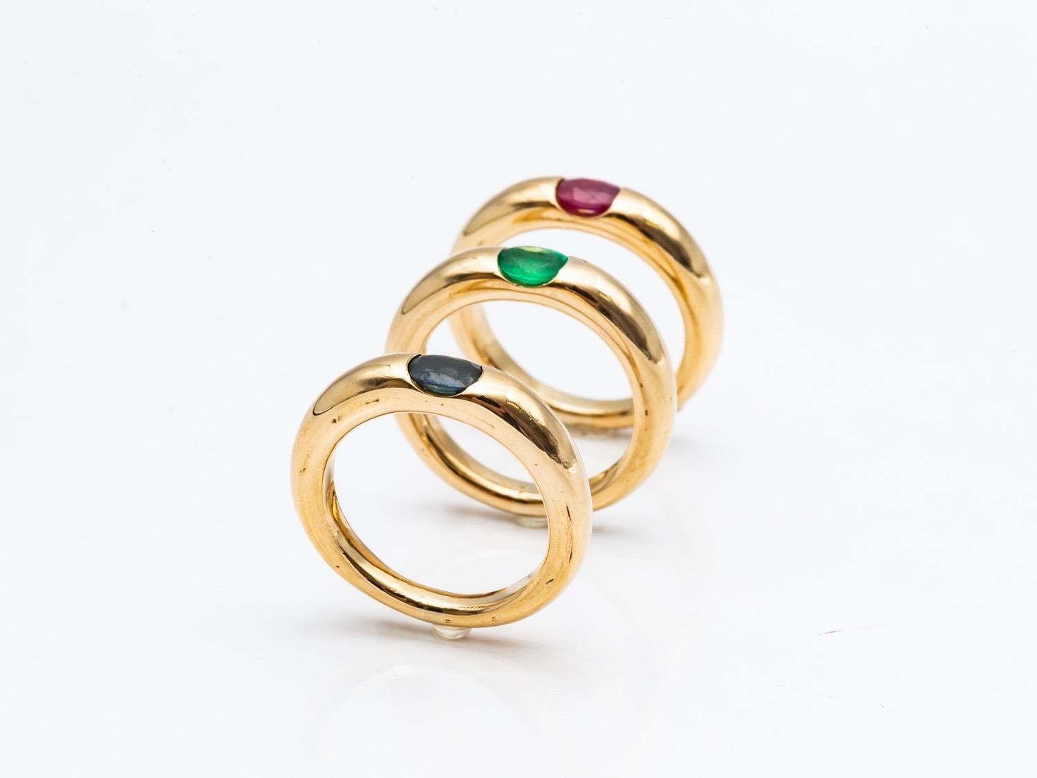 Oval Cut Three 18 Karat Gold Bangles Rings Set with an Emerald, a Sapphire, and a Ruby