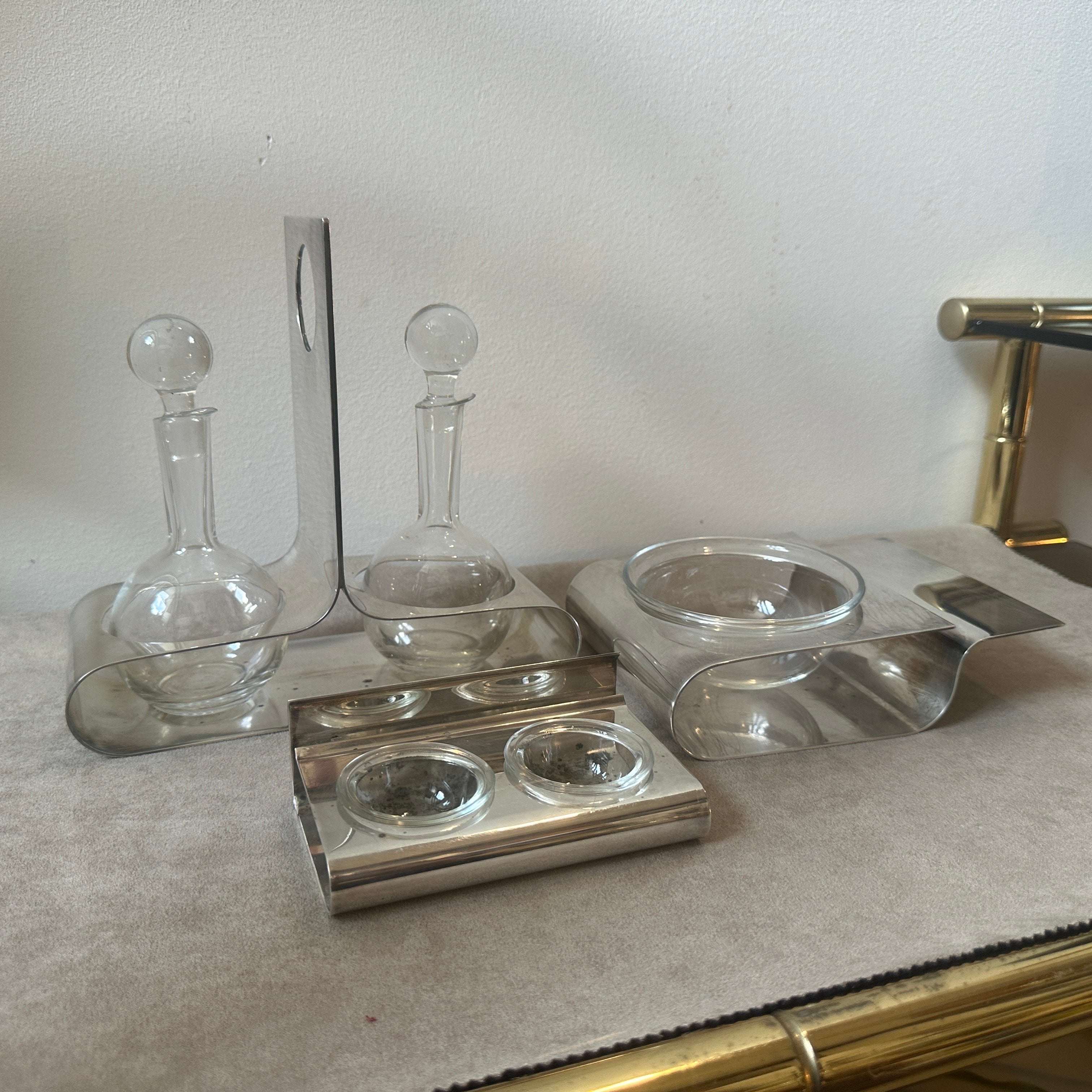 
This silver-plated set designed by Lino Sabattini is composed of a cruet for oil and vinegar with crystal glass ampoules, one cheese bowl, and a salt and pepper shaker. The dimensions of the other two pieces are 17x12 cm and 12x8 cm, respectively.
