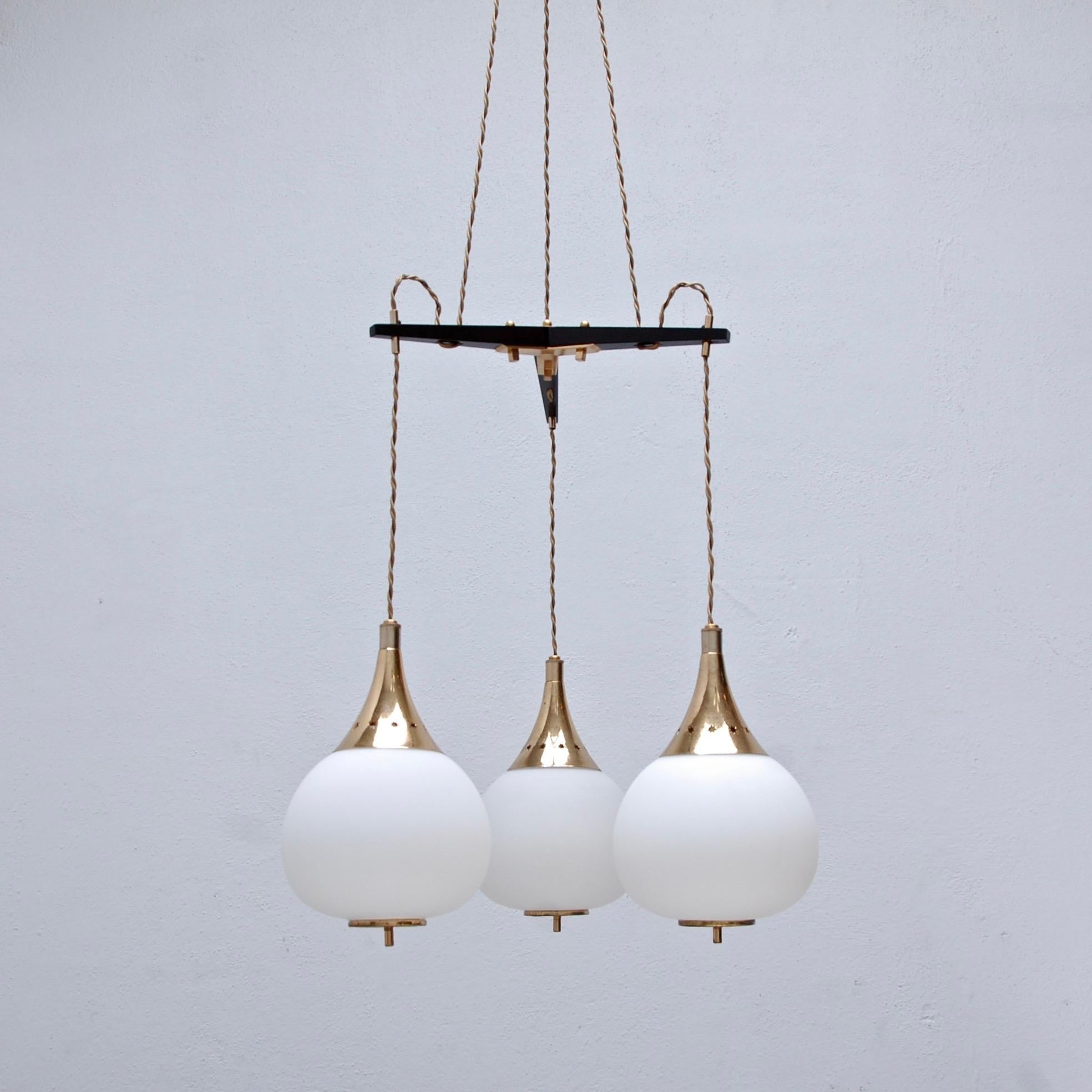 (2) iconic 1950 pendant chandeliers by Stilnovo of Italy. Each pendant has its original aged brass finish, (3) glass globe shades and wood centre spacer. Wired for use in the US. Current OAD can be adjusted upon request. Single E12 candelabra based