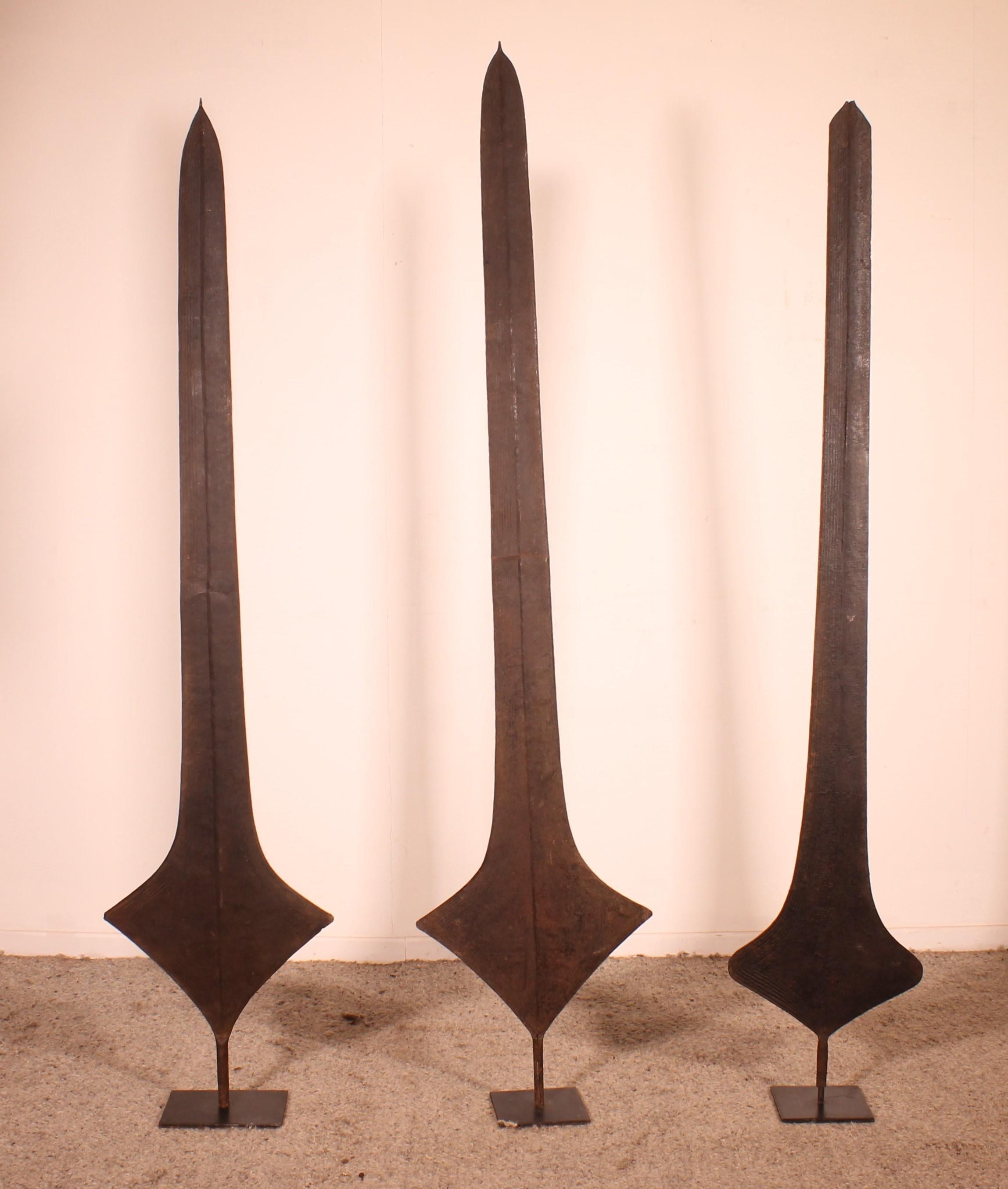 Trois lames de monnaie ou épées africaines en fer, provenant des peuples Topoke de la République démocratique du Congo, joliment présentées sur un support métallique personnalisé. Ces lames étaient utilisées par divers groupes tribaux en République