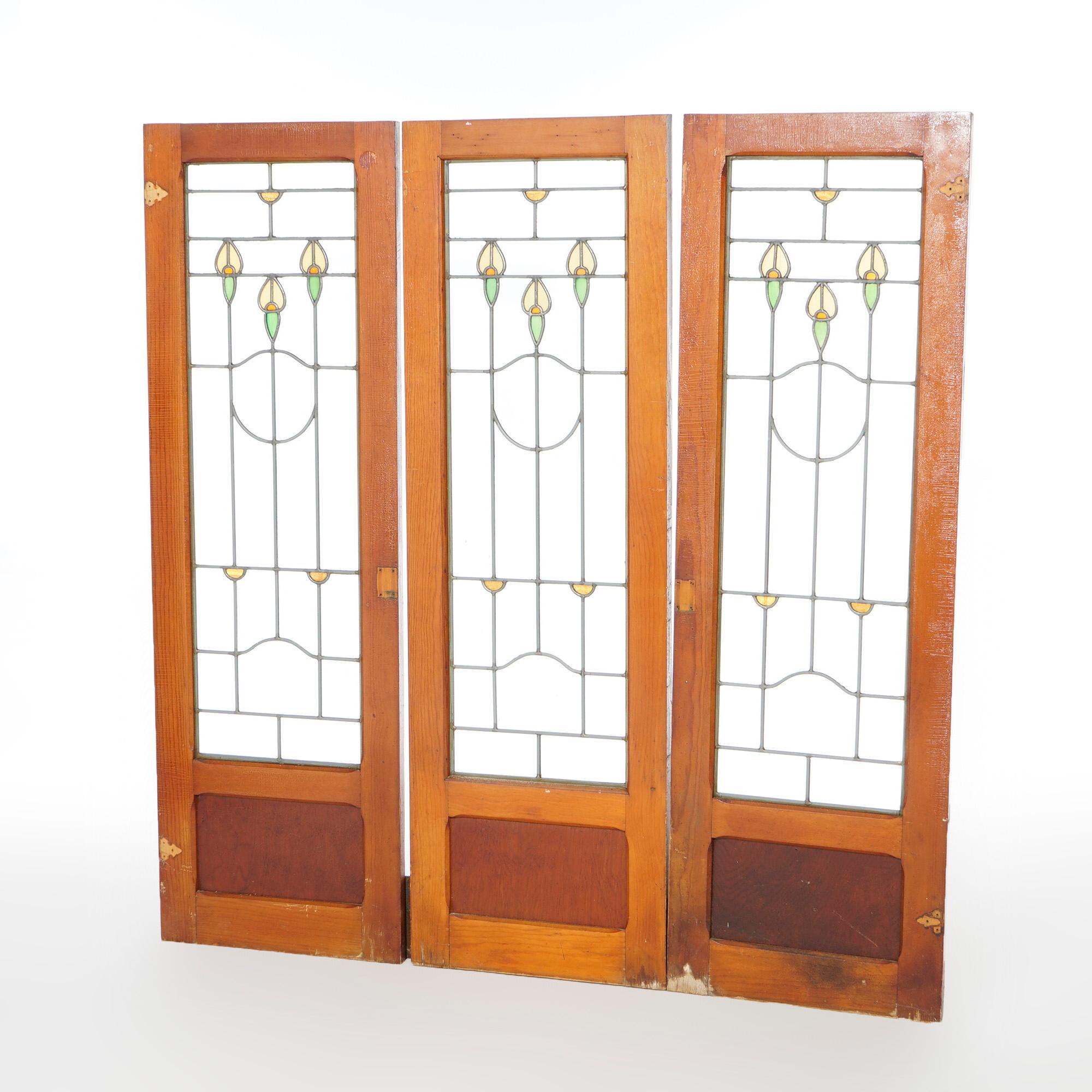 An antique set of three Arts and Crafts Prairie School leaded glass windows offer stylized floral elements, seated in wood window frame sashes, c1910

Measures- 58''H x 18.5''W x 1.25''D

*Ask about DISCOUNTED DELIVERY rates within 1,500 miles of NY*