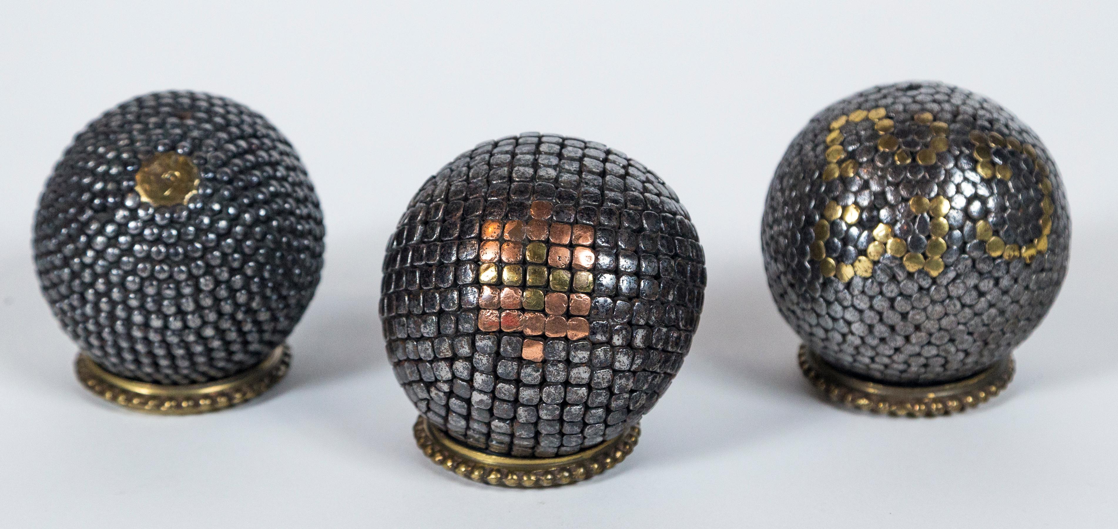 Three Antique Pétanque Balls, France, late 19th Century. Solid wood center, covered in hammered, steel nails with accent brass and copper nails. Brass rings as shown are for display. Petanque is the French version of Italian Bocce.