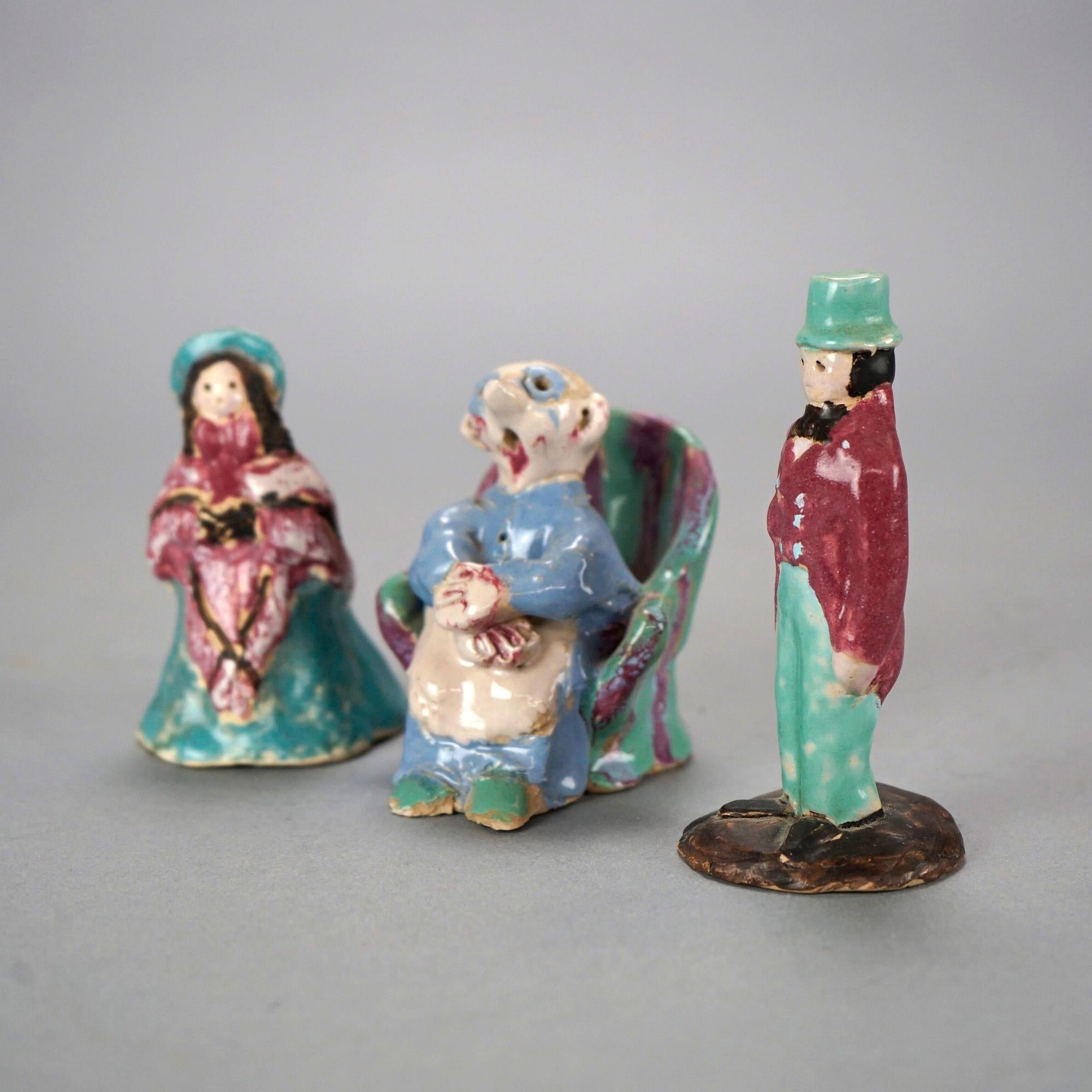 A set of three figurines by Overbeck offer art pottery construction and depict a man in a top hat, a seated woman and a standing woman in a Victorian dress, maker mark as photographed, c1920.

Measures- Seated woman 3.25'' H x 3.5'' W x 2.5'' D;