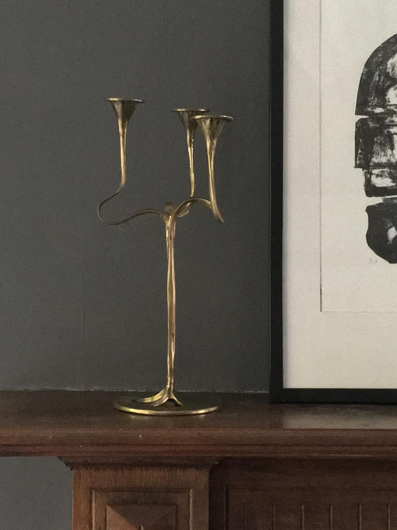 A three-arm candlestick of organic, ribbon form, evoking Art Nouveau style. 

The piece is made of solid brass and is in good original condition with a nice patina. There minor age-appropriate signs of wear, including faint scratches, spots of