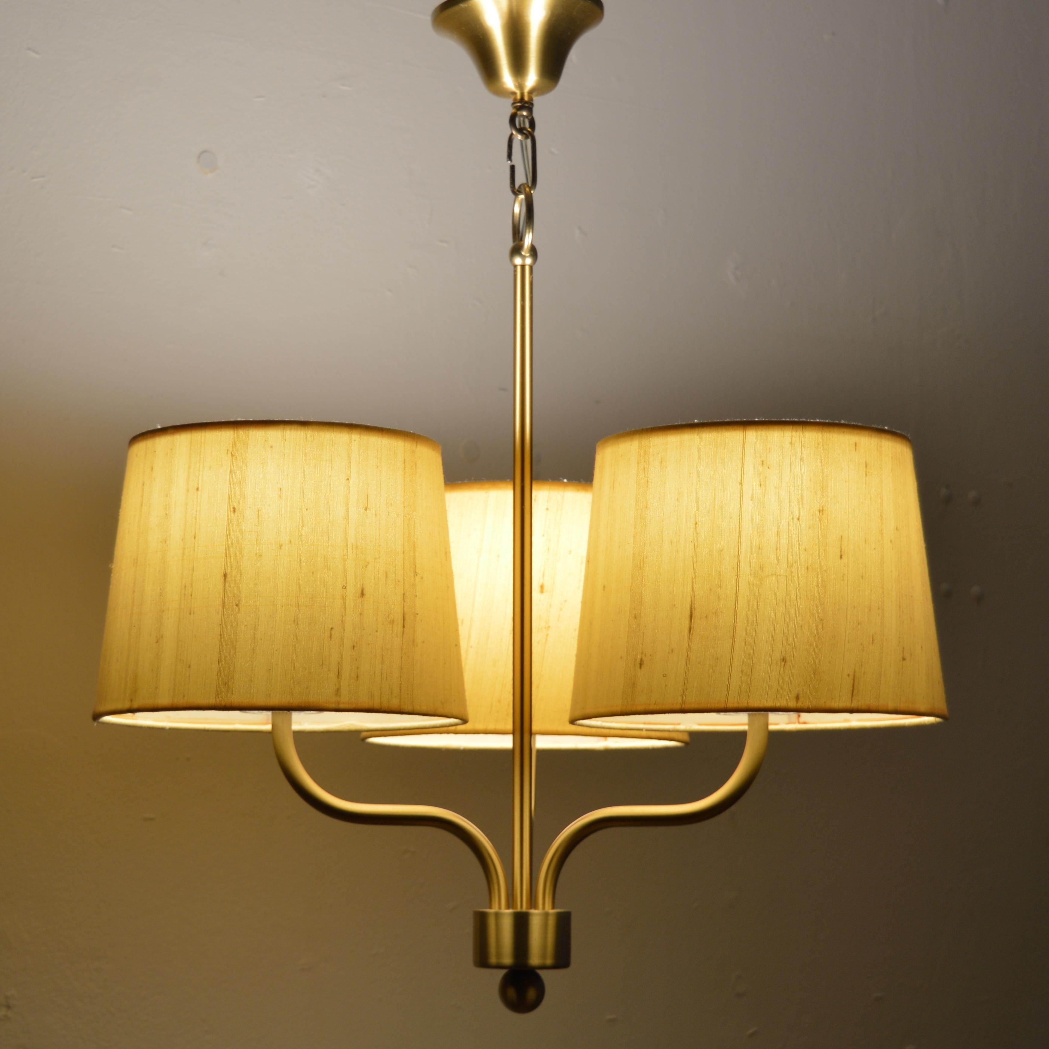 ‎‎Swedish lighting manufacturer, Luxus gave form to some of the now iconic models that define the “Swedish mid-century style”. This brass three-light chandelier was created in this “golden age of Scandinavian design”, a period that saw the revival