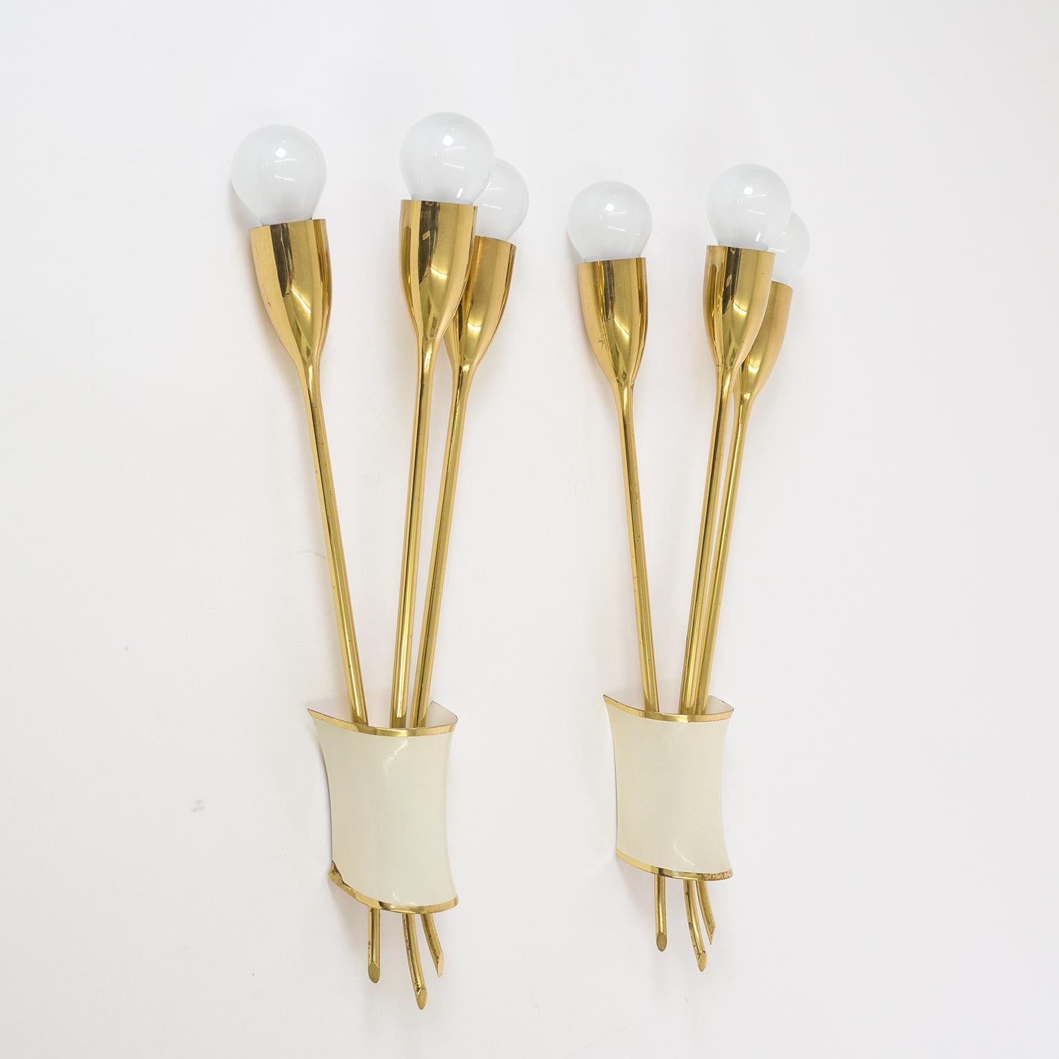 Beautiful brass sconces attributed to Kalmar, early 1950s. Made entirely of brass these three-arm sconces are gorgeously crafted. Note how the socket covers blend seamlessly into the stems. The brass cover which hides the wall support is lacquered