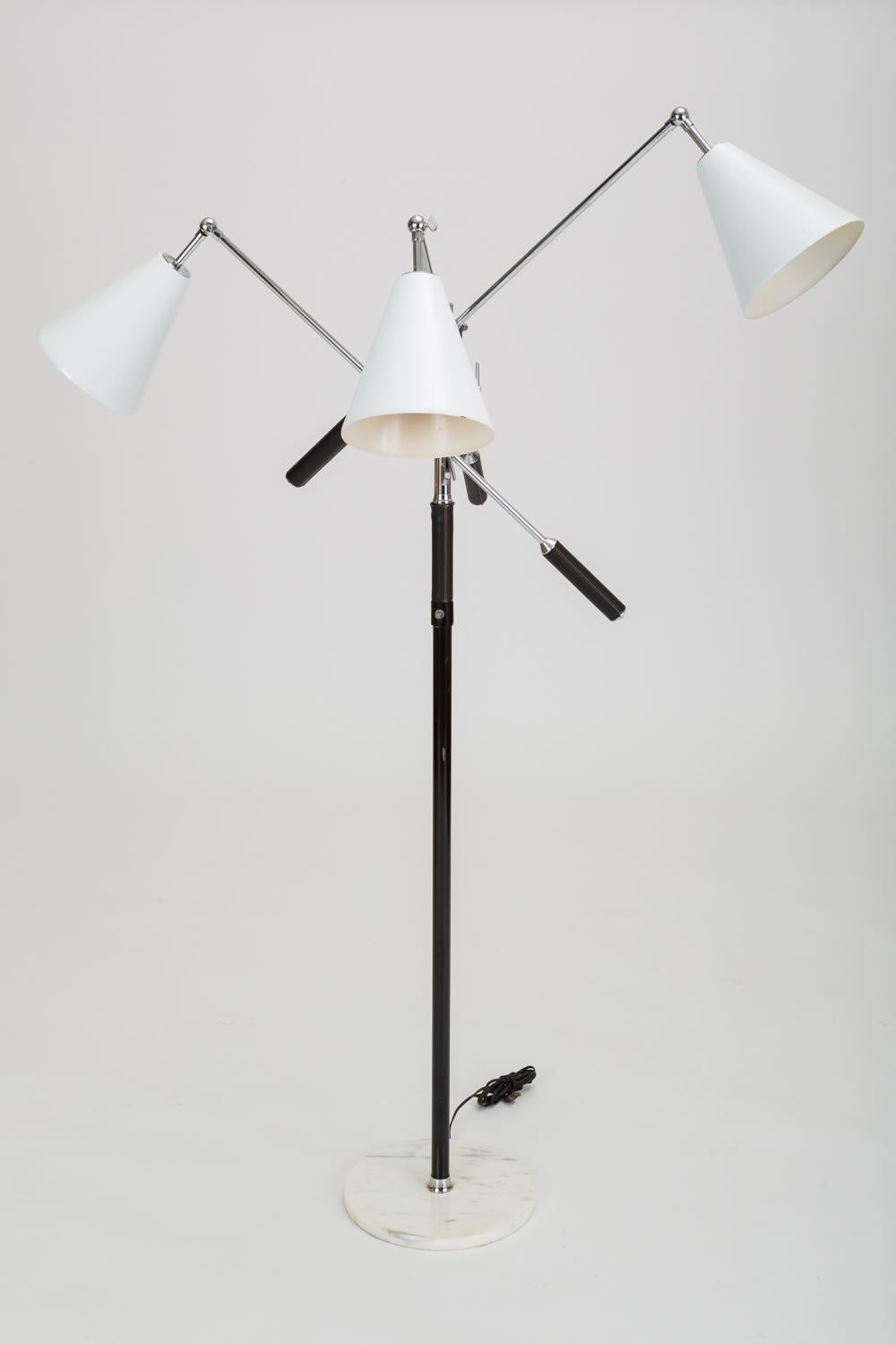 An Italian modernist lamp from the 1950s. The tall floor lamp has a round base in Carrara marble, a central steel post wrapped in leather with ivory contrast stitching, and three counterbalanced arms, each terminating in an adjustable lampshade of
