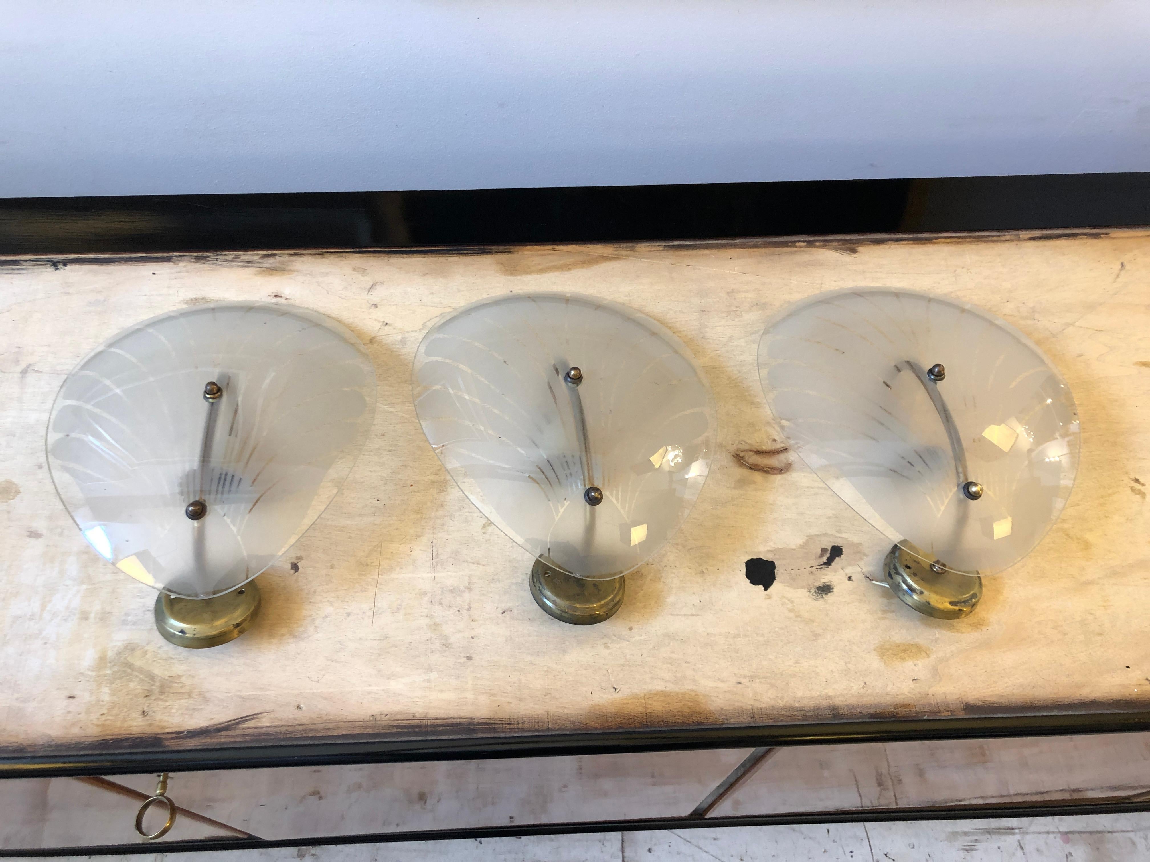 Three Art Deco wall sconces designed and manufactured in Italy in 1940 sold one by one. Glasses are in perfect conditions, brass it's in original patina. They work both 110-240 volts and need regular e14 bulbs. Art Deco design was prominent during