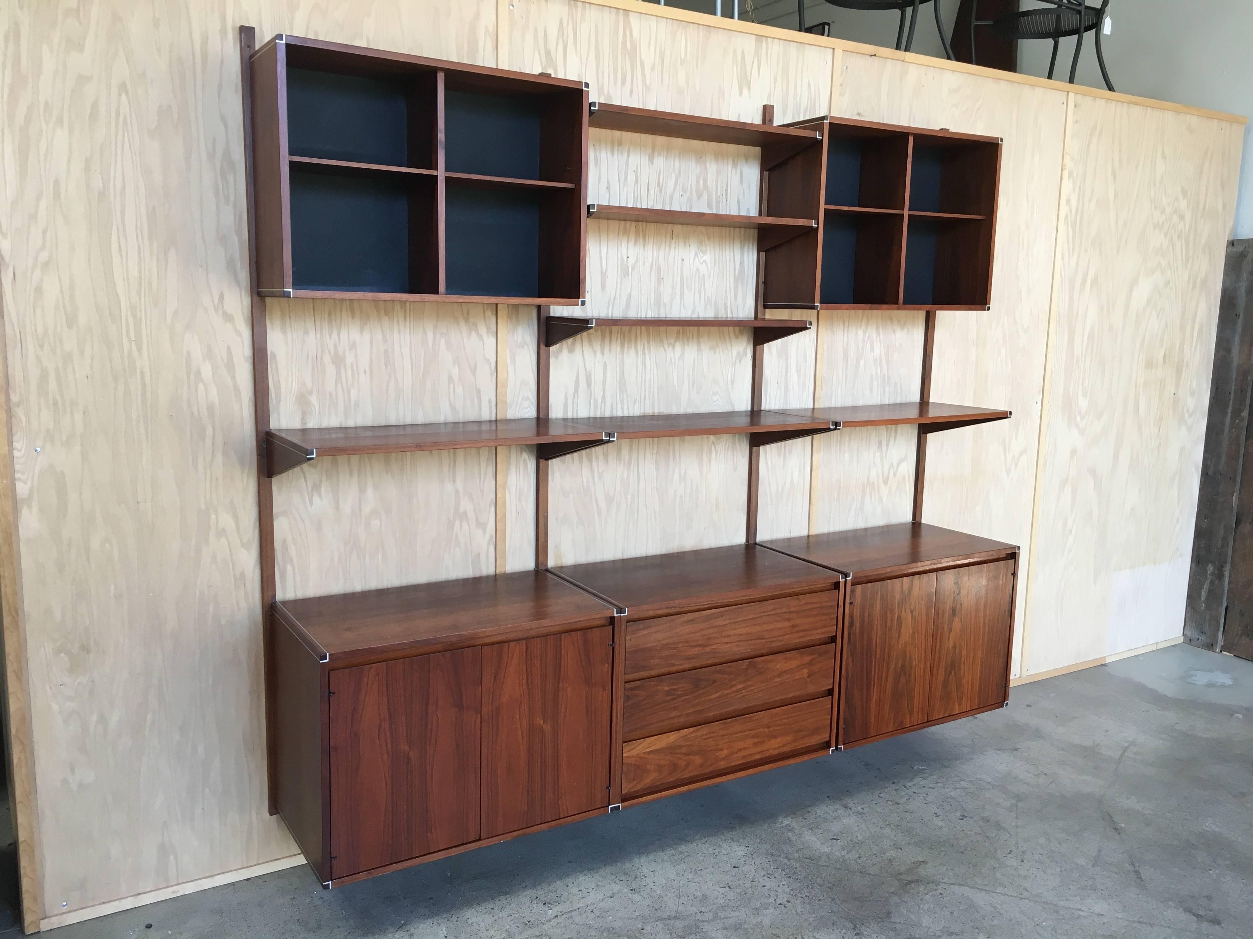 Walnut with metal trim three bay hanging wall unit. fully adjustable. With two doored cabinets and one drawer section and assorted shelves Made by Barzilay.