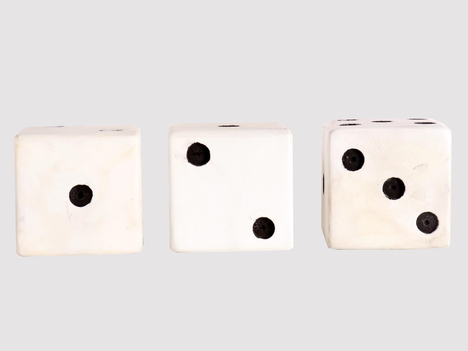 Three large dice, made of white painted wood. On the six sides of the cube, circles from 1 to 6 are engraved and painted in black. USA, circa 1940.