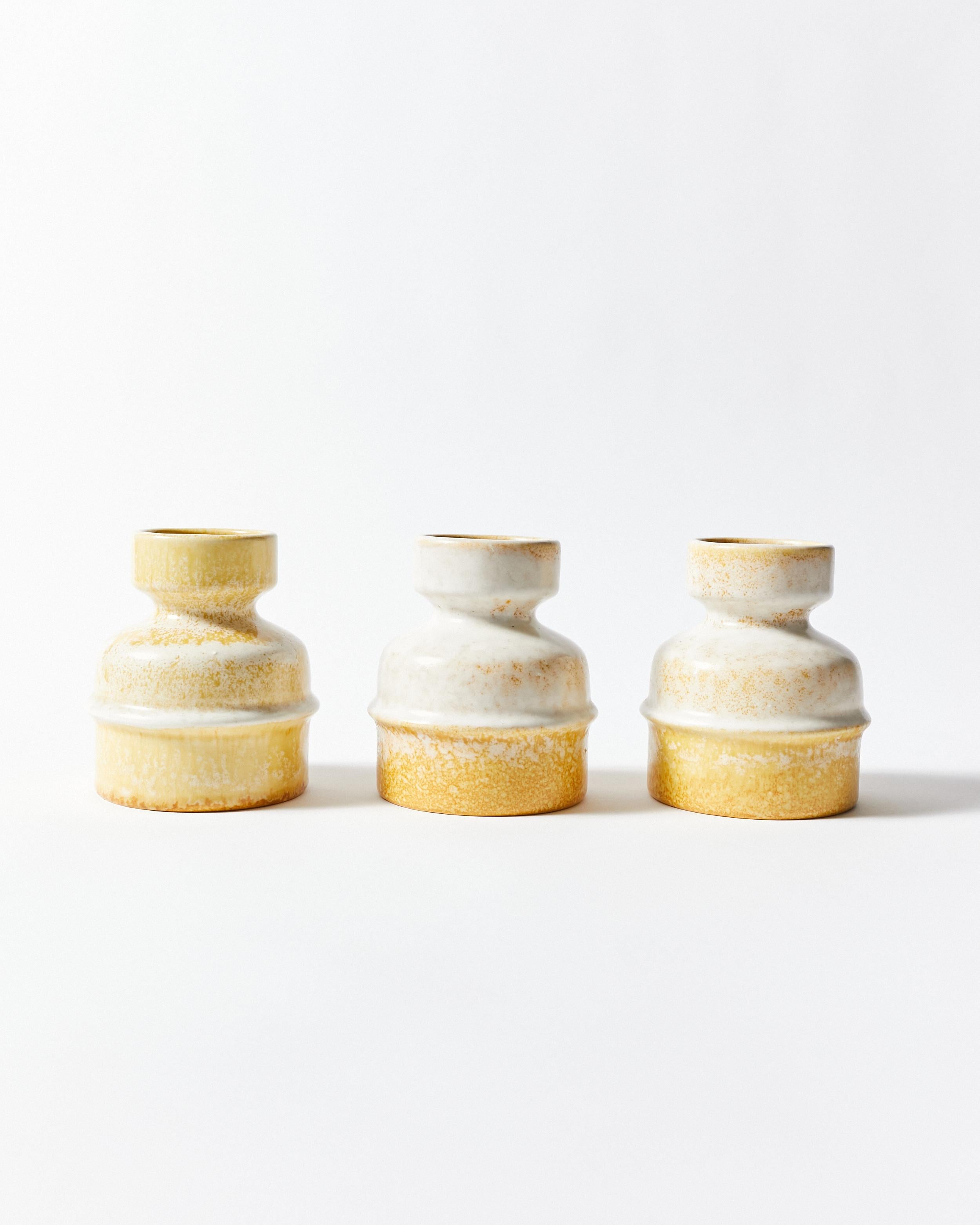 Trois vases courts en céramique. Produit par Jasba Keramik, Allemagne de l'Ouest, années 1970. Ces pièces sont sculpturales et presque brutalistes. Les trois vases sont finis dans un beau ton satiné blanc et jaune glacé. Ils sont signés du logo