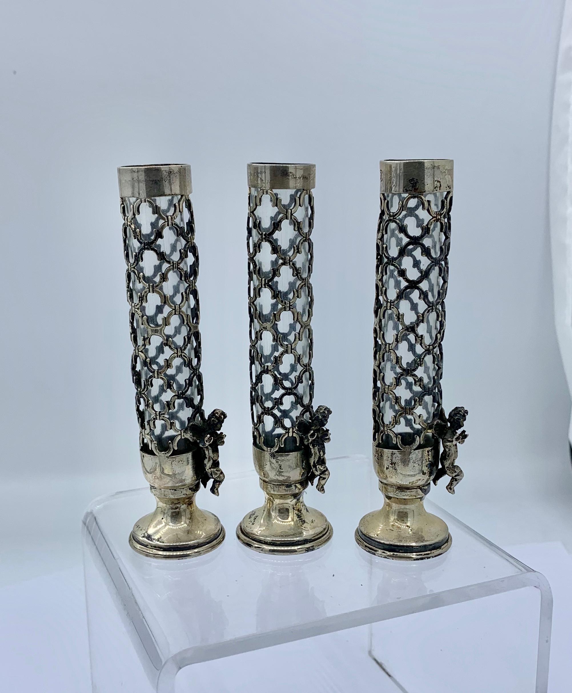 THIS IS A WONDERFUL SET OF THREE VICTORIAN - BELLE EPOQUE SILVER FLOWER BUD VASES ADORNED WITH GORGEOUS WINGED FLYING CHERUB, ANGEL OR CUPID PUTTI.
The vases are silver and have a lattice open work design.  Each vase has a flying angel towards the