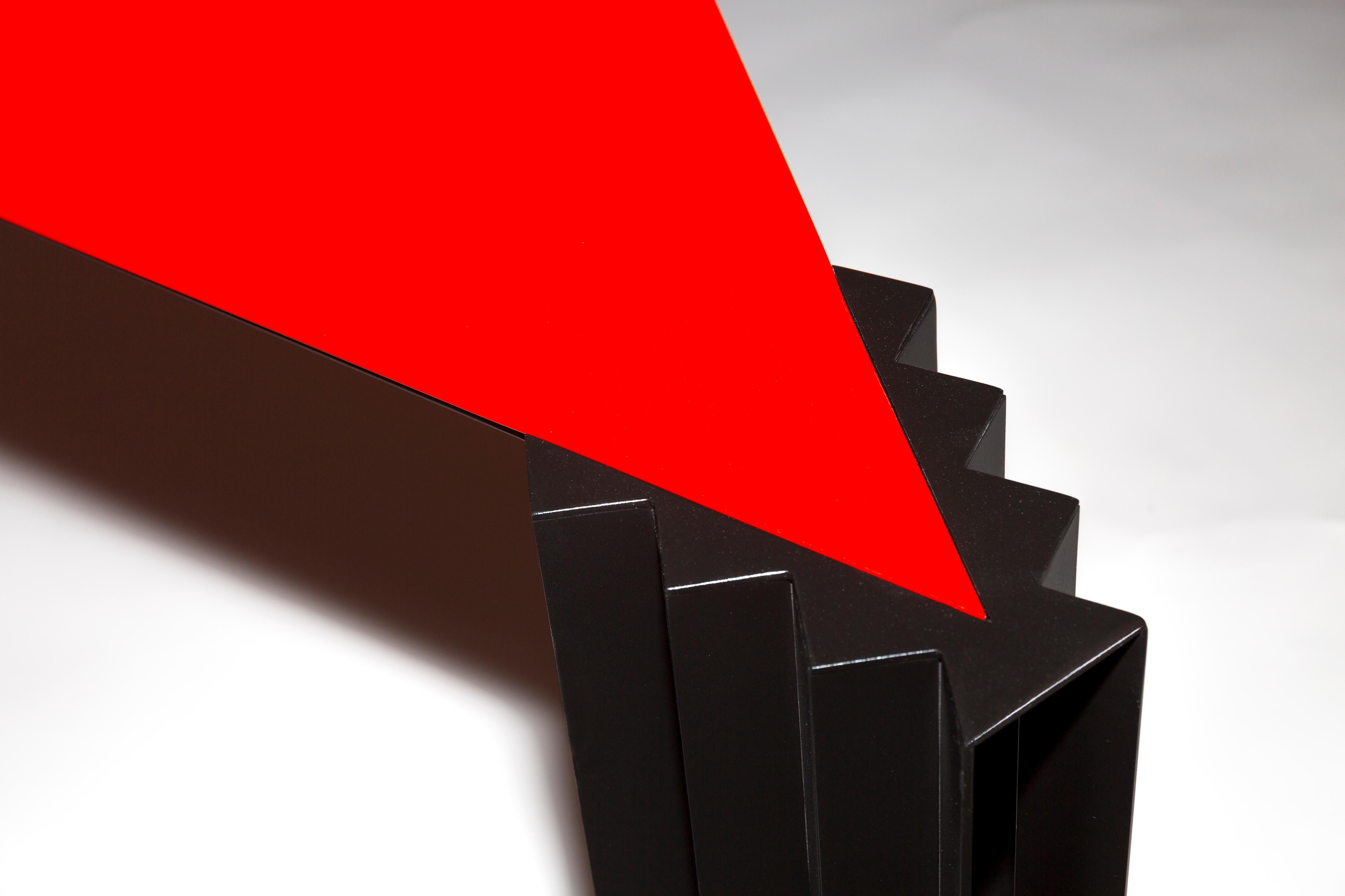 Trois coins, trois colonnes est une table dynamique à souhait.  Un triangle d'acier rouge brillant s'imbrique parfaitement dans la surface des trois pieds, qui explorent chacun une nouvelle forme.  Sur l'une d'elles, des barres métalliques se