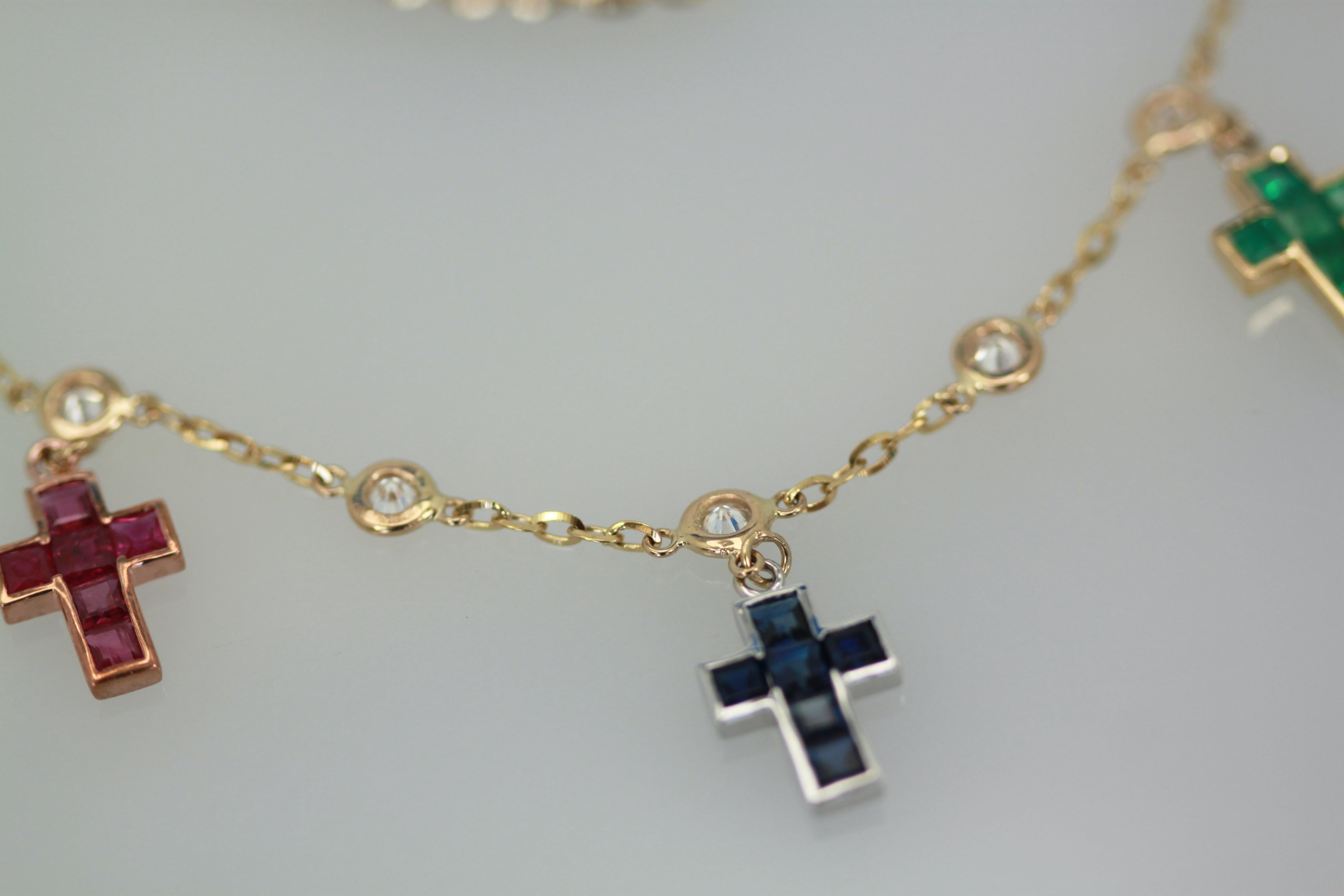 This lovely necklace is set with Diamonds and crosses.  There is one Ruby, one Sapphire, one Emerald Cross all in baguette stones with round Diamonds on top and between.  These are set on an 18K Yellow gold chain of 20