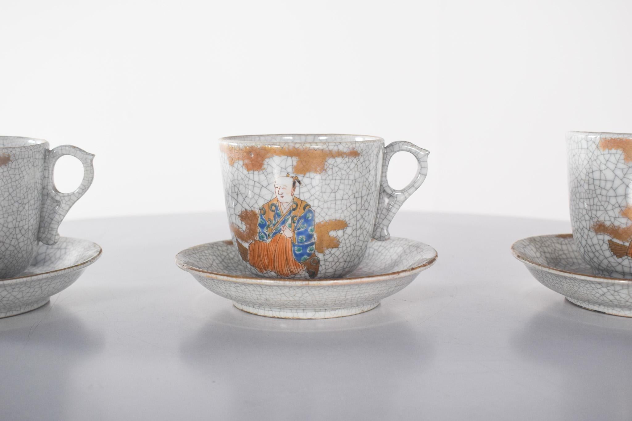 Three cups and saucers made from Japanese porcelain. The porcelain is fine and has a craquelé effect.
The decoration is oriental-inspired, featuring traditional Japanese figures dressed in richly detailed kimonos in shades of blue, orange and gold.