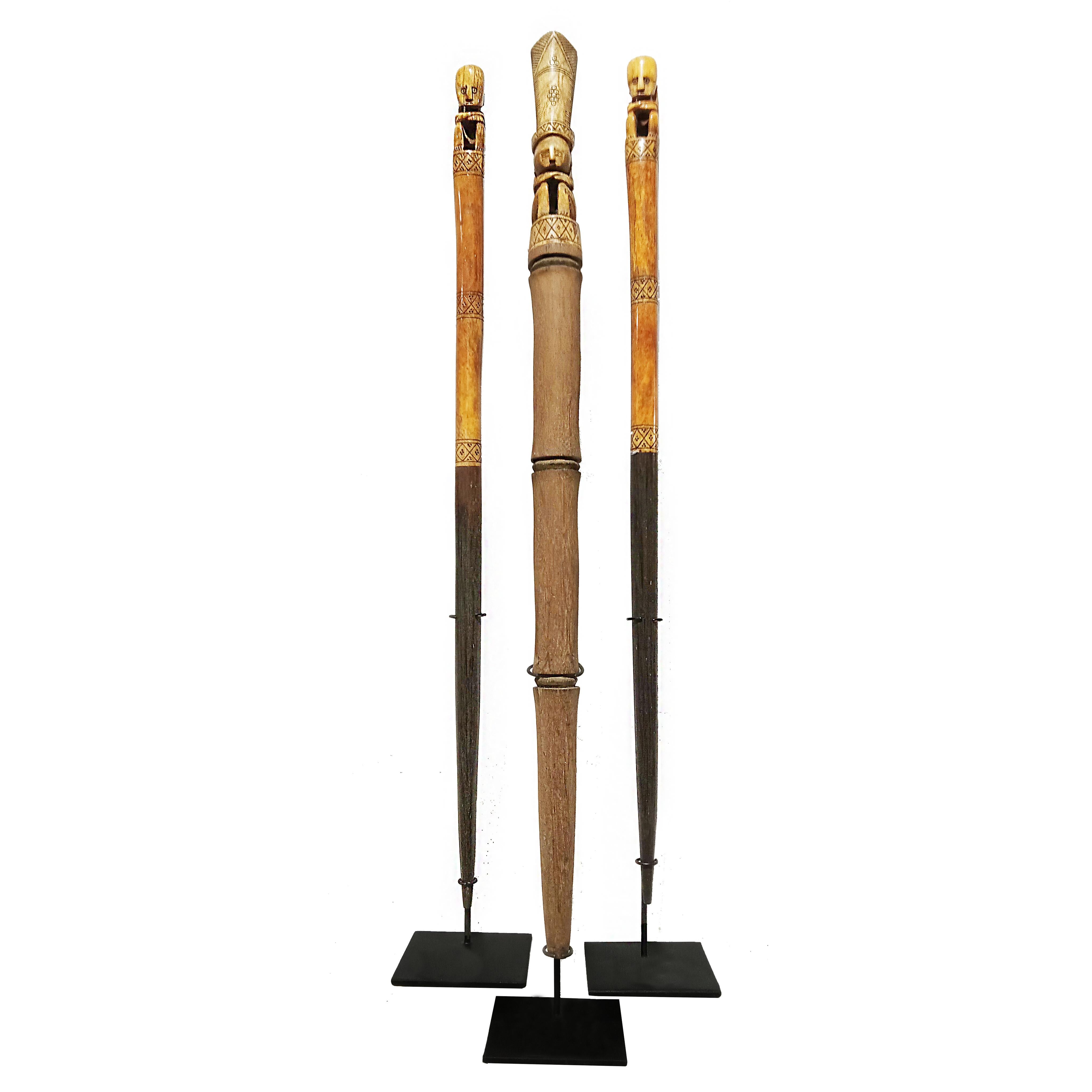 Three wooden batons, hand-carved in Indonesia, late 20th Century. 

Two of the batons are made in two-tone Suar wood, dark at the lower part, and lighter on the top part, ending in a delicately carved sitting man. The third baton is made out of