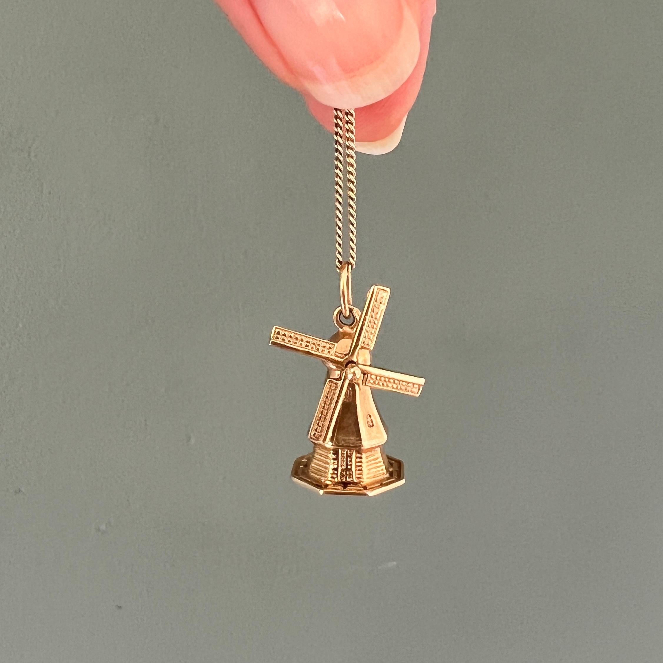A large three-dimensional Holland windmill charm pendant. The octagon windmill is made in 14 karat gold and is nicely detailed with horizontal 'beams' on the hull and windows on the attic floors. The blades of the windmill are movable and can spin