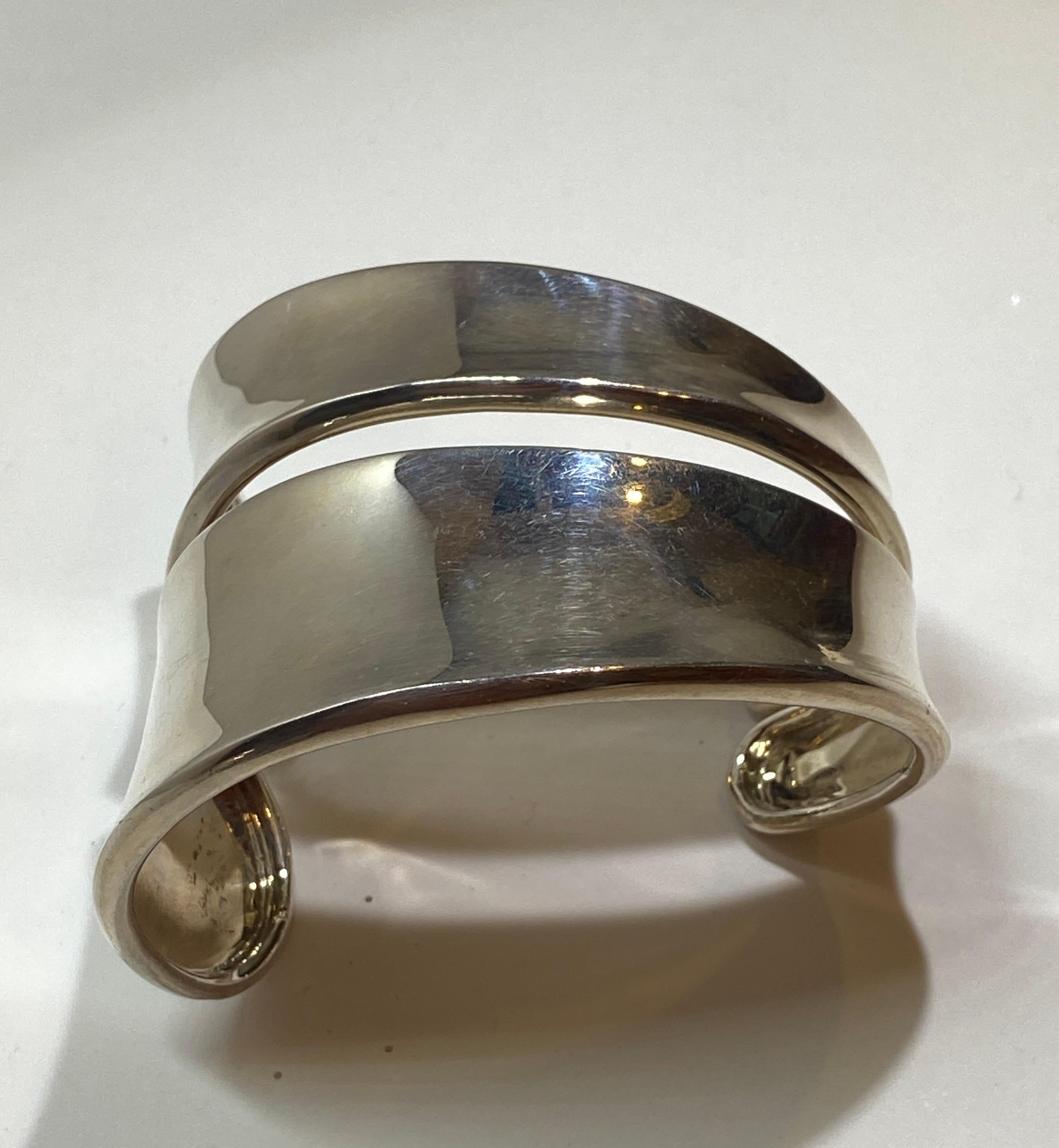 This wonderfully elegant three-dimensional Yvone Christa polished sterling silver cuff bracelet measures 7 1/8 in circumference. The width varies from 7/8 of an inch to 2 inches. Maker's mark is etched along the interior. Made in US.