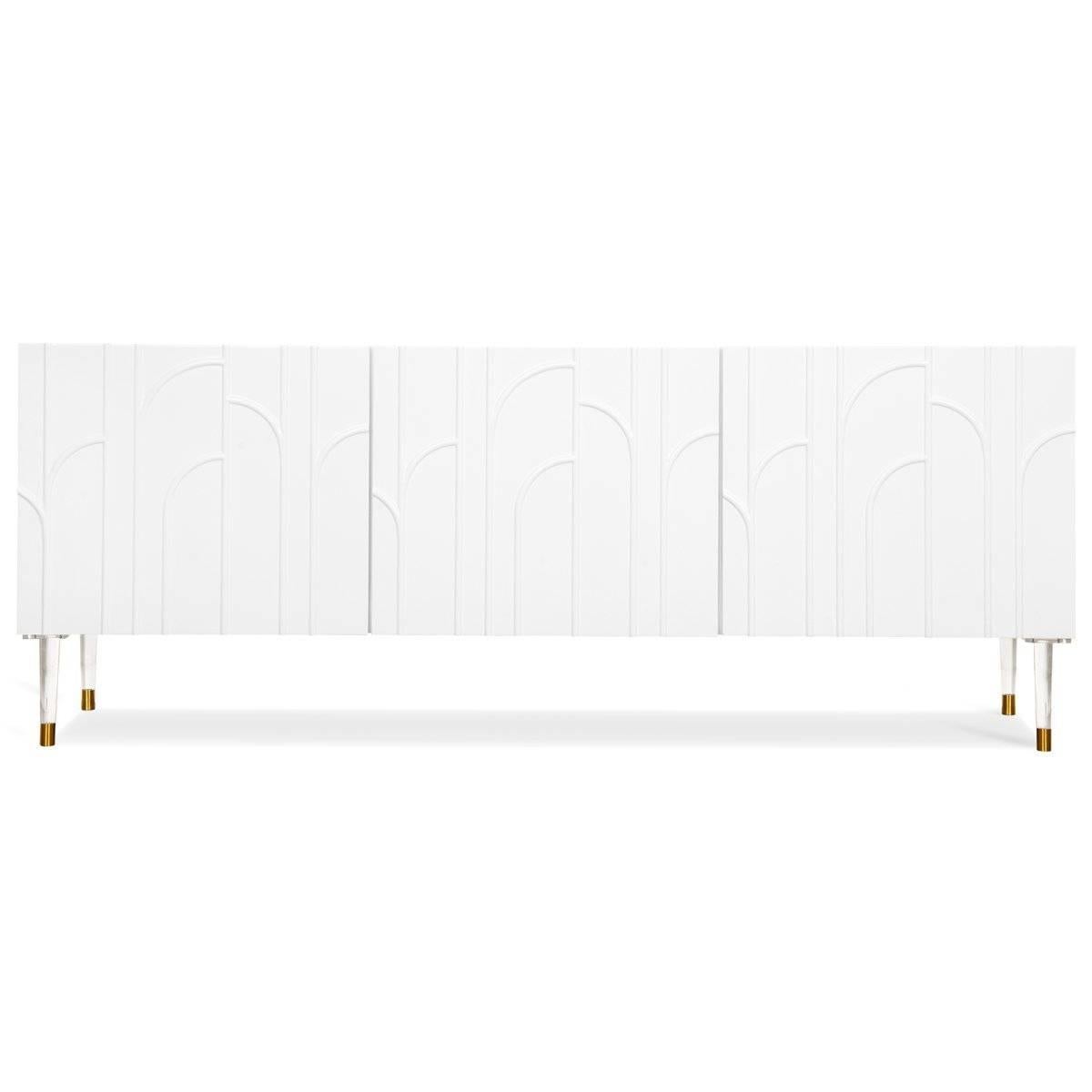 Introducing the Provence three-door credenza. This beautiful credenza features a matte white body with a striking Art Deco-inspired facade and tapered Lucite and brass legs. Inside the credenza, you will find adjustable-height shelving and plenty of