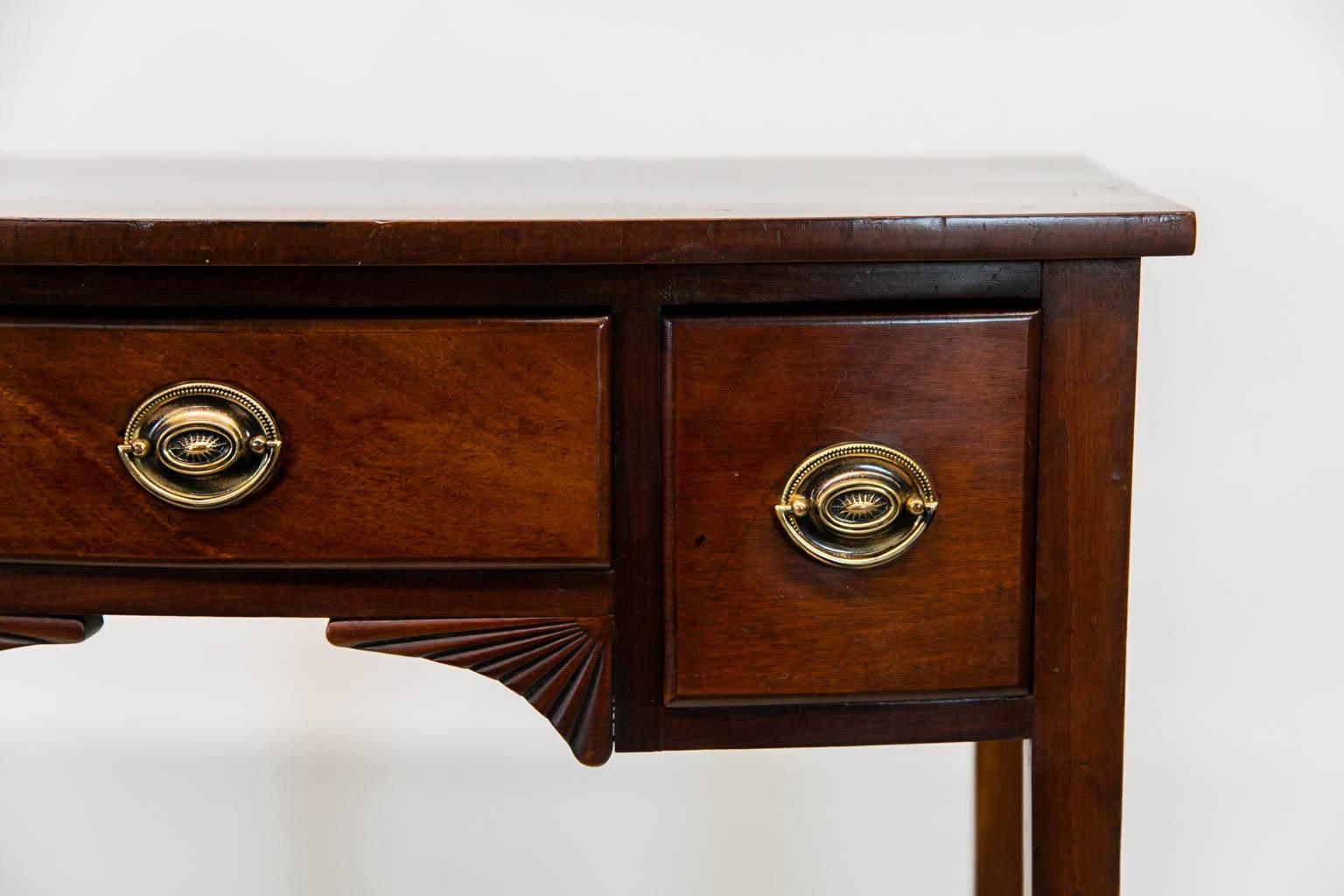 This mahogany server has a bowed front. The center apron has stylized carved fans. The hardware is later.