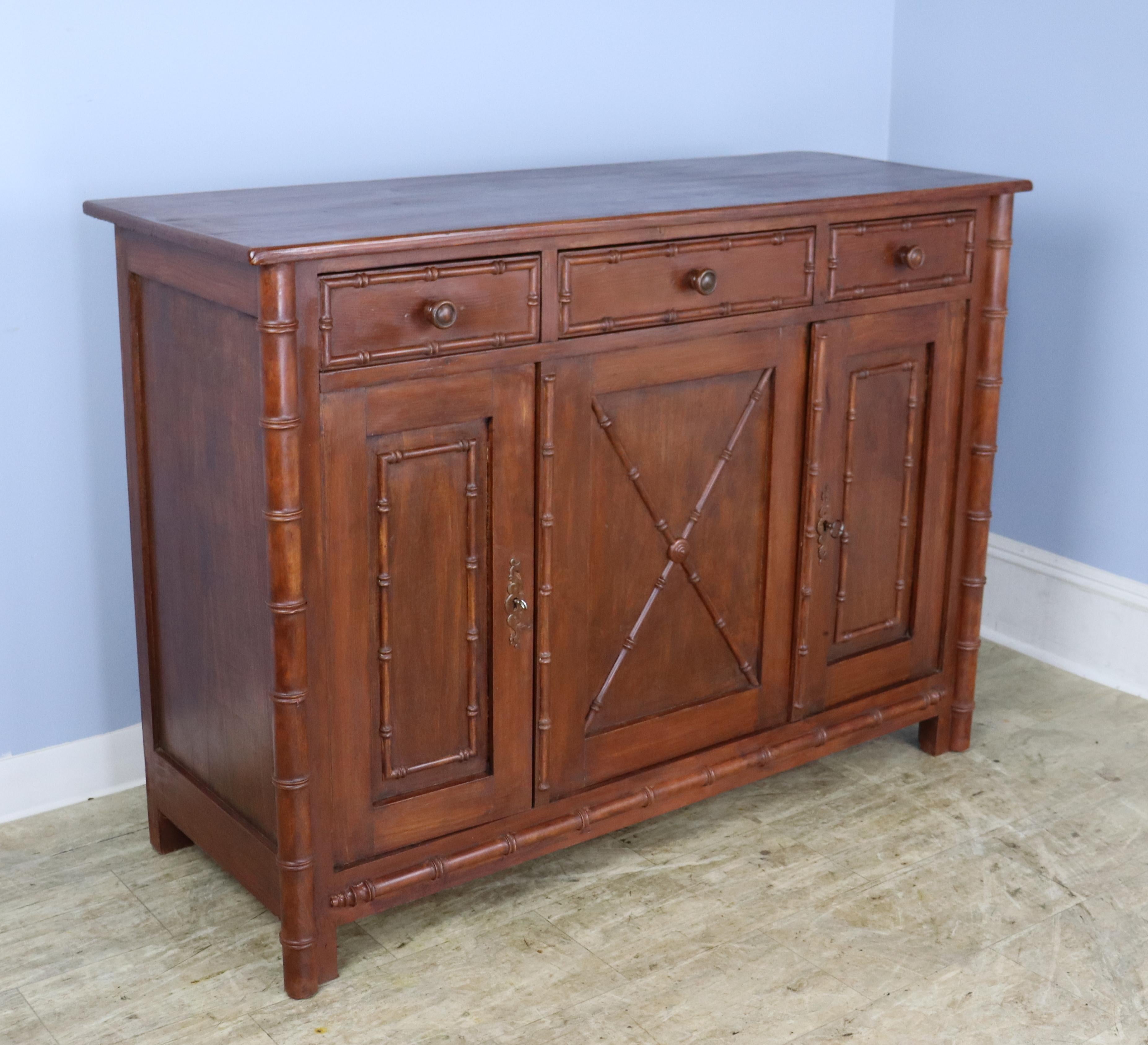 A three door enfilade or buffet with three compartments and a non-adjustable interior shelf.  Both doors lock easily with a key, though the right door has a slight warp at the top, visible in the thumbnails.  The bambood trim and mouldings are