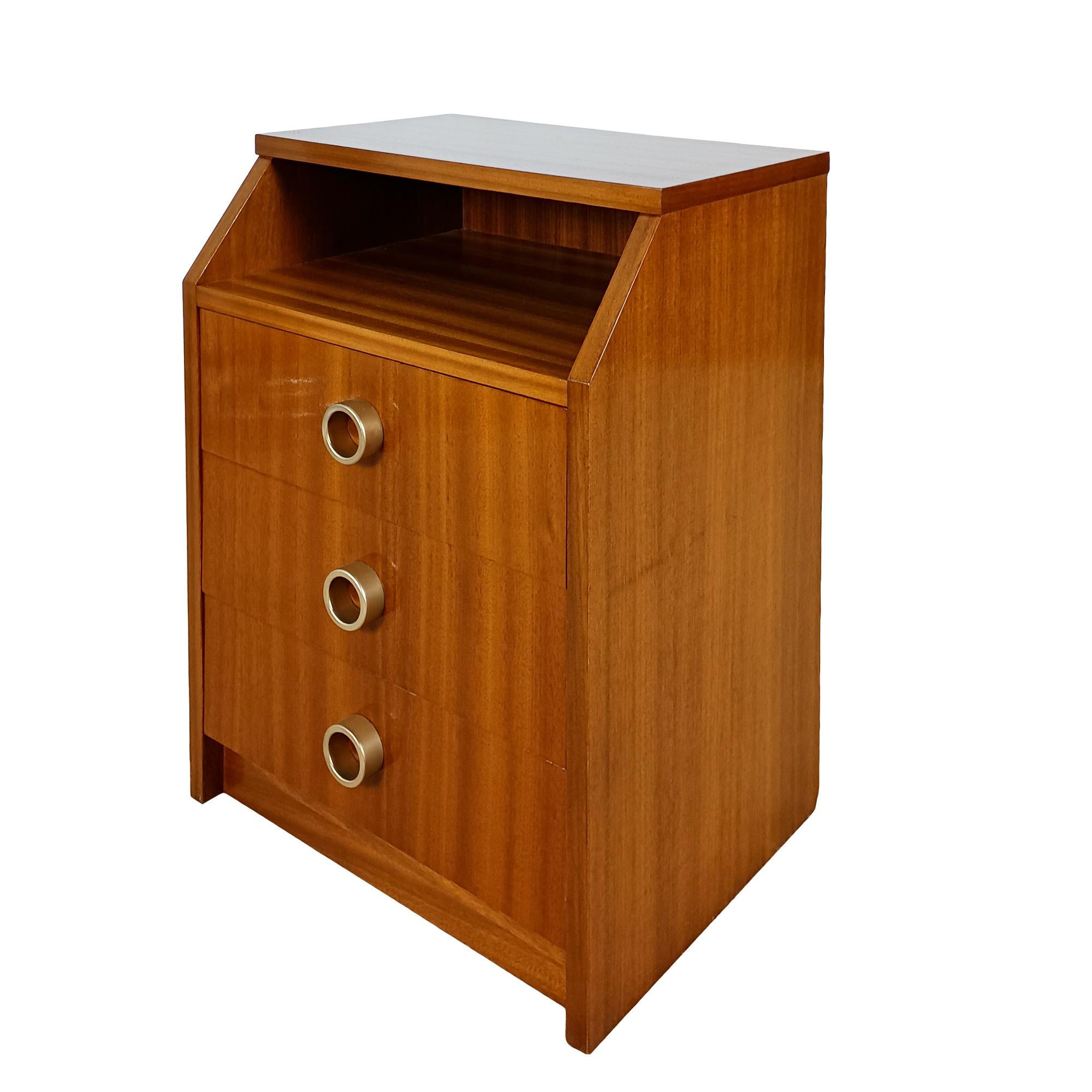 Table de chevet à trois tiroirs, bois massif avec placage de sapelli, poignées en métal doré. Finition à la gomme-laque.

Espagne 1960-1970

