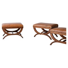 Three elegant ottomans with padded leather seat.