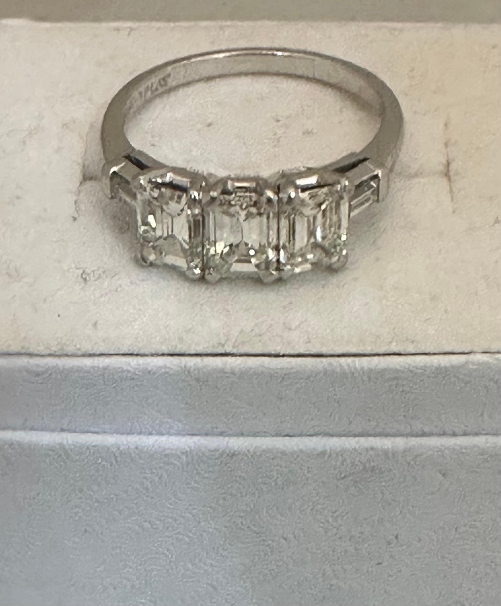 This vintage 1960s ladies platinum/ diamond ring is designed with three emerald cut diamonds & two baguettes. The total of the three center diamonds is 1.80 carats & the two baguettes weigh a total of 0.12 carats. The band is stamped platinum. The
