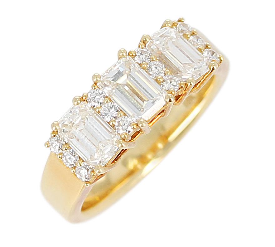 A Three Stone Emerald-Cut Diamond Band with Round Diamonds in 18 Karat Yellow Gold. The Diamonds weigh 1.22 carats, Total Weight: 5.42 grams. Ring Size US 5.75. 