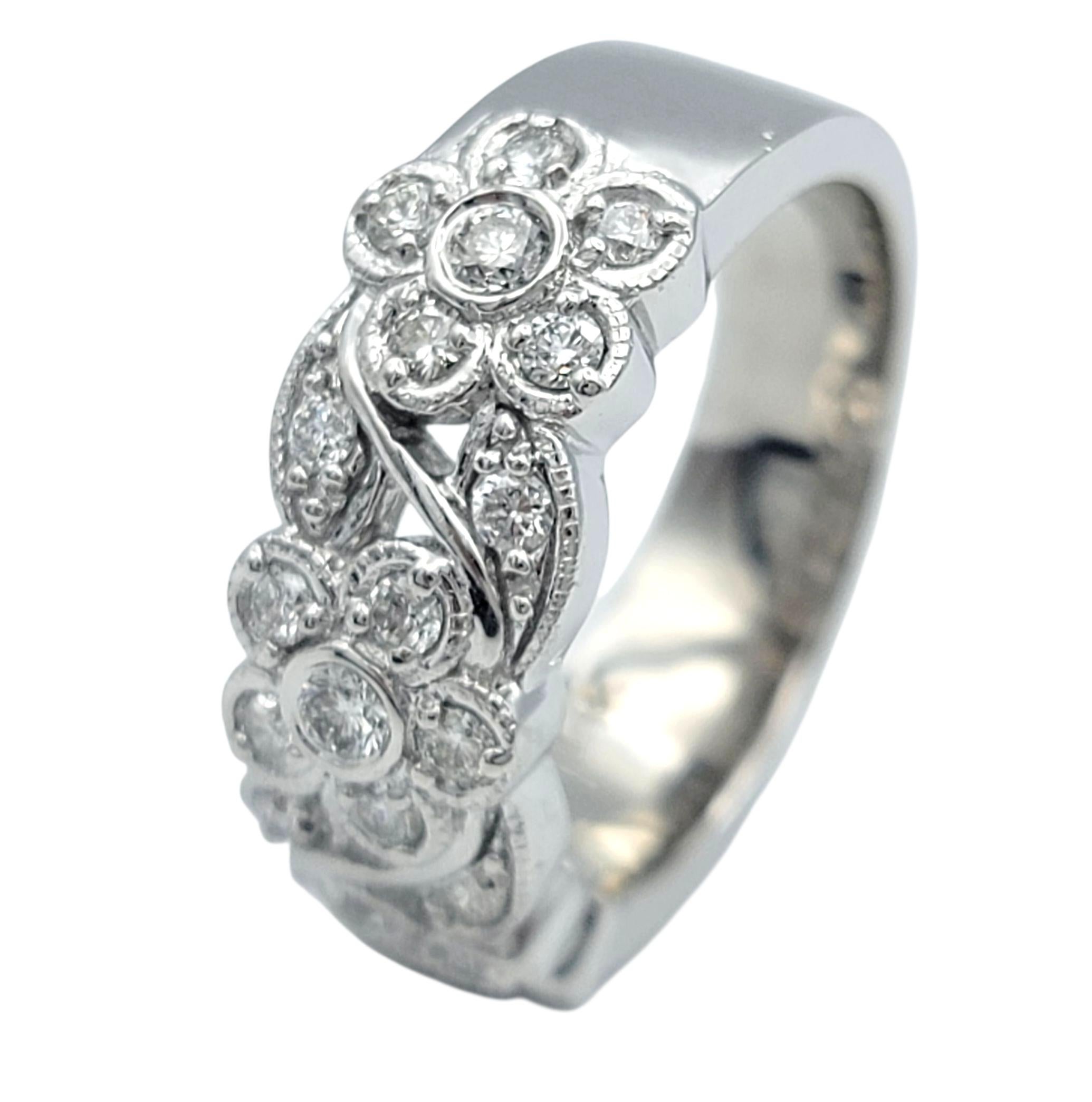 This enchanting diamond ring captures the beauty of timeless design with its intricate floral motif. Crafted in 14 karat white gold, the band features a series of delicate openwork flowers, each petal and swirl glimmering with diamonds that sparkle