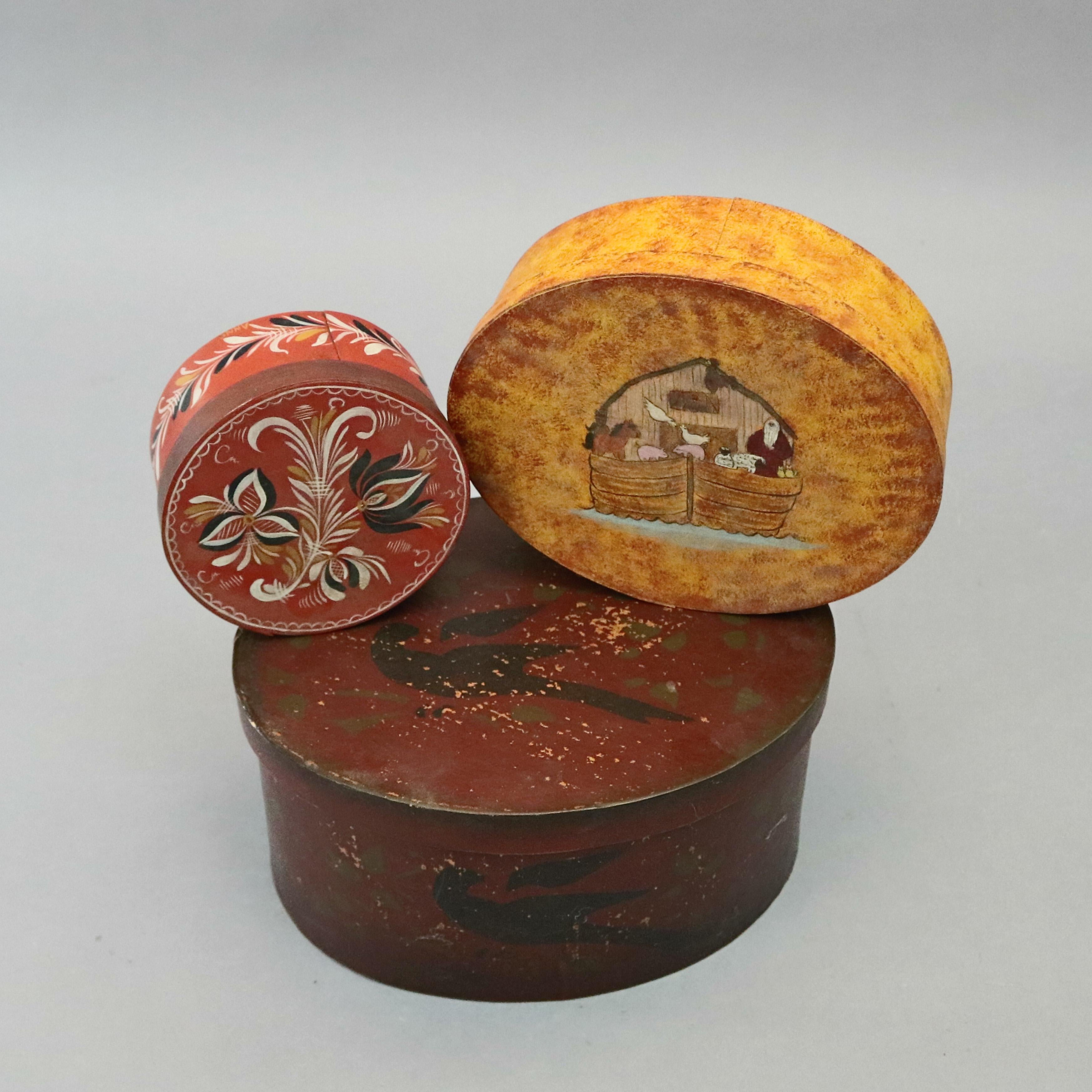 Three Lesher School Shaker boxes offer bentwood maple and birch pegged construction in oval form with Gothic-shaped finger joints (swallowtails) finished in copper tacks, paint decorated in Folk Art designs including black bird, Noah's Ark and