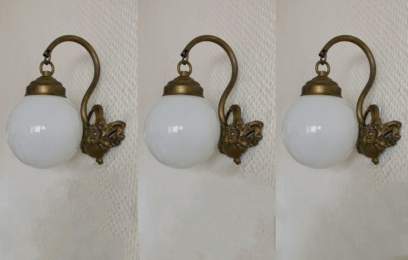Set of three  lovely bronzed brass wall sconces with opaline glass ball globes, for indoor and covered outdoor use, France, 1930-1939. Beautiful bronzed brass flower basket shape as wall mount.
All three pieces sconces are in very good condition,