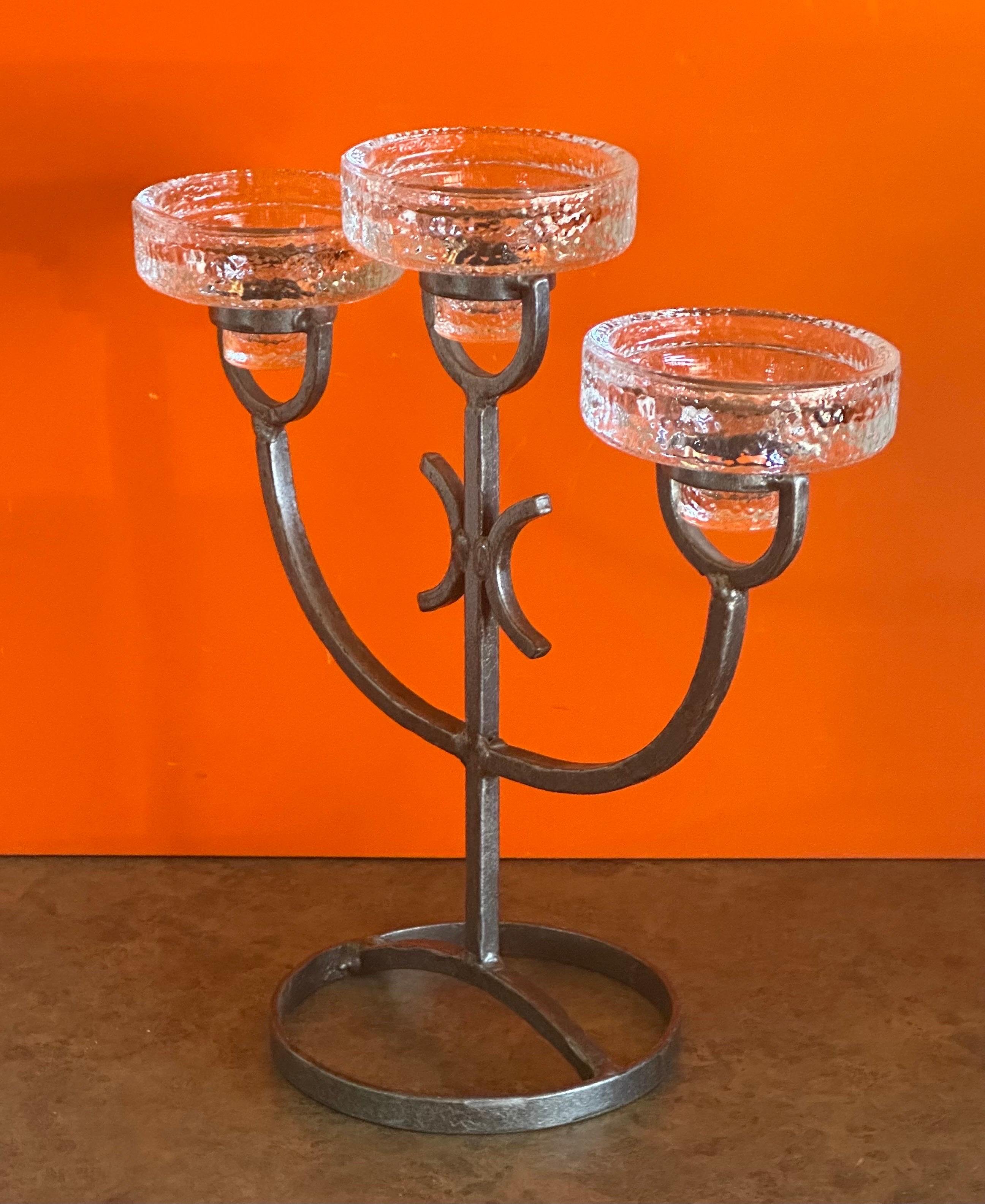 Ein schöner Kerzenständer aus handgehämmertem Eisen mit drei Gläsern von Erik Hoglund für Kosta Boda, ca. 1960er Jahre.  Das Stück ist in sehr gutem Vintage-Zustand ohne Chips oder Risse auf dem Glas mit dem Eisen Basis zeigt eine wunderbare Patina.