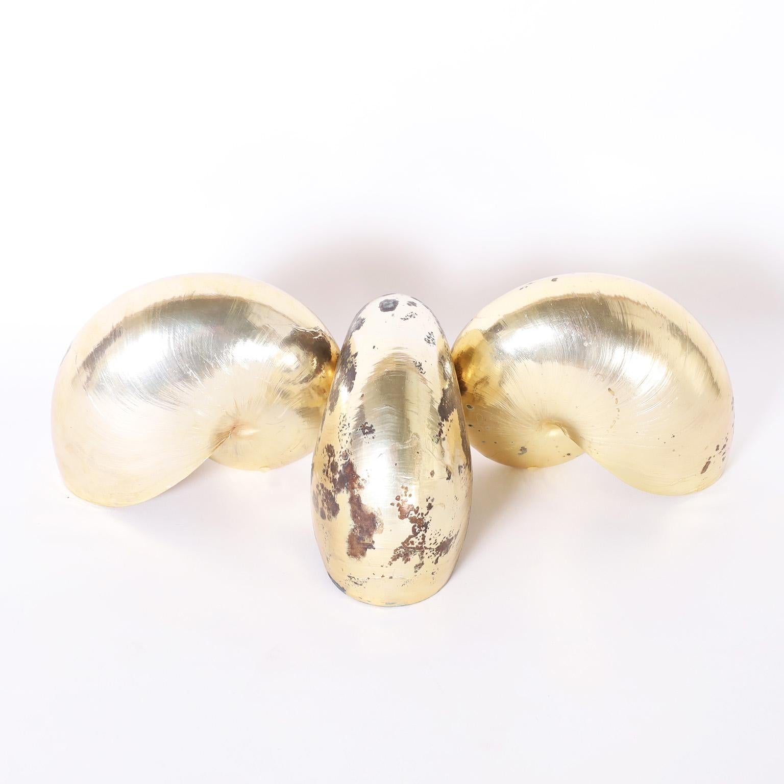 Group of three nautilus shells with their iconic form, gold plated with a copper under coat wearing through as a sculptural element.