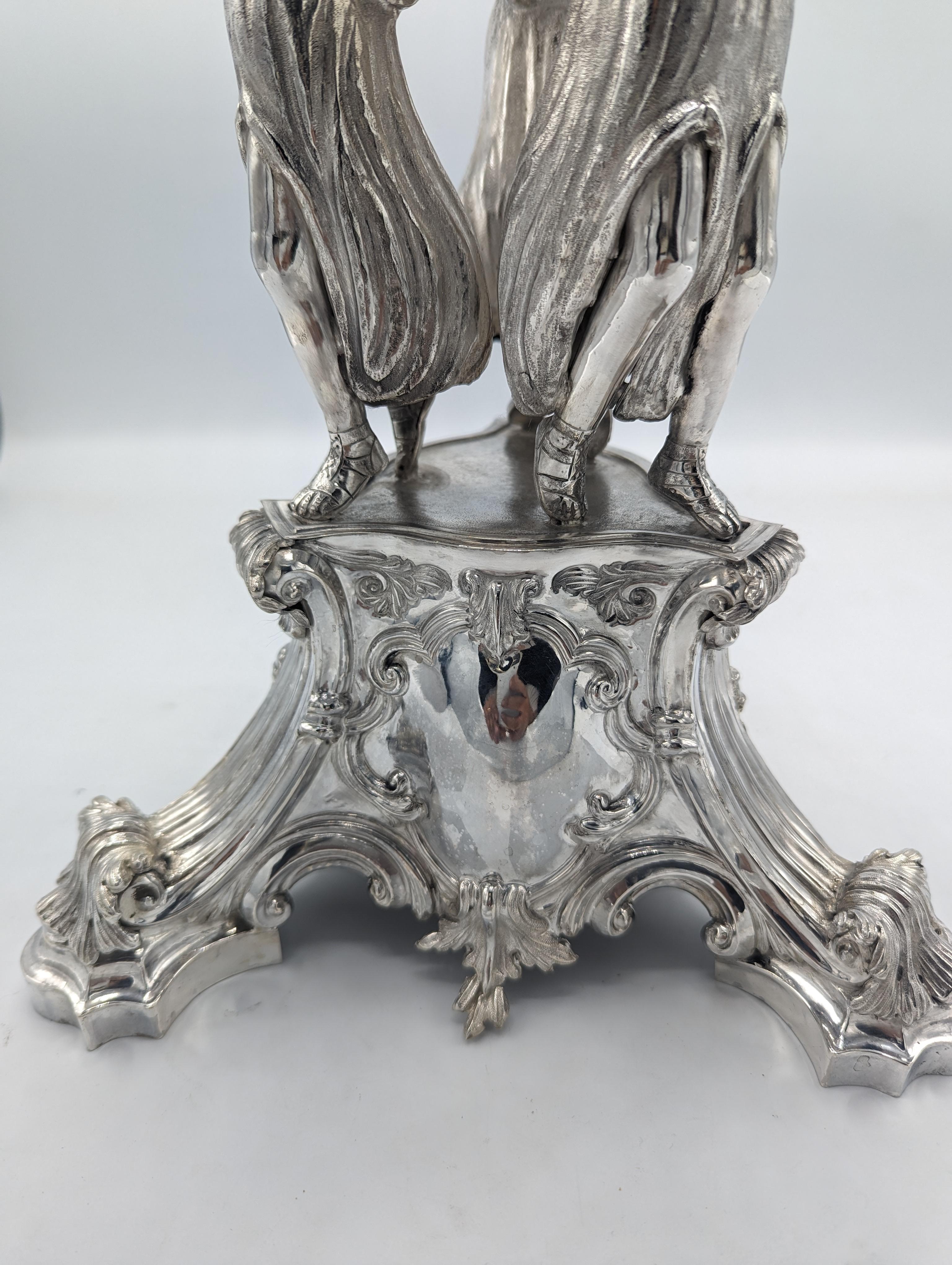 This stunning centerpiece is a work of art with a touch of history. Handcrafted by Helaria, renowned silversmiths, it features the three graces,   Aglaia, goddess of radiance and beauty; Euphrosyne, goddess of good cheer, joy and mirth; and Thalia,